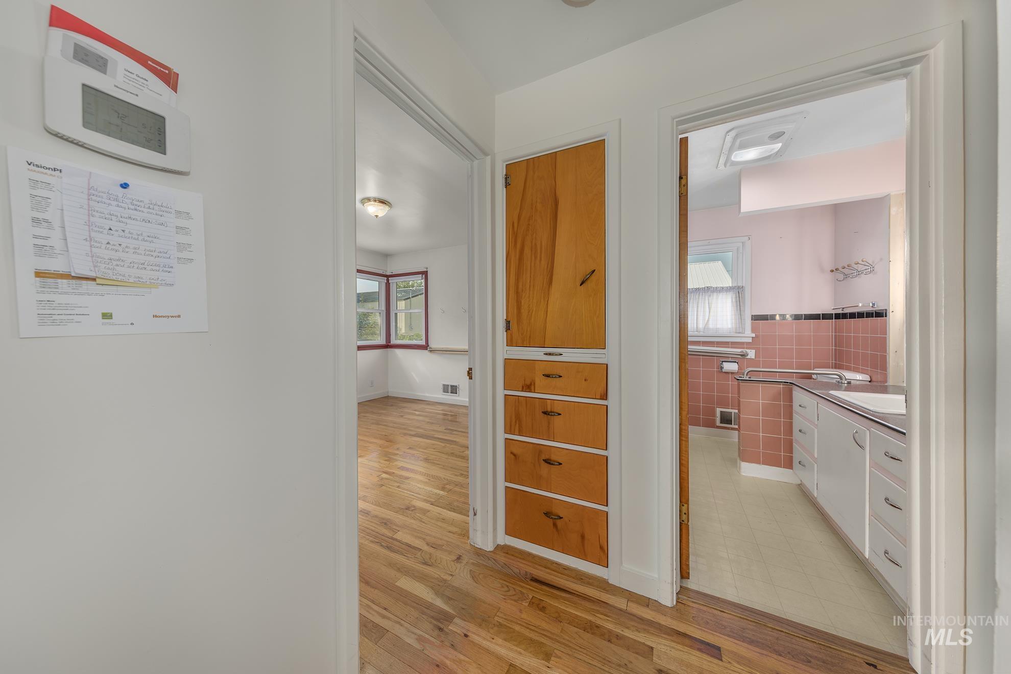 Hall featuring light wood finished floors, tile walls, and wainscoting