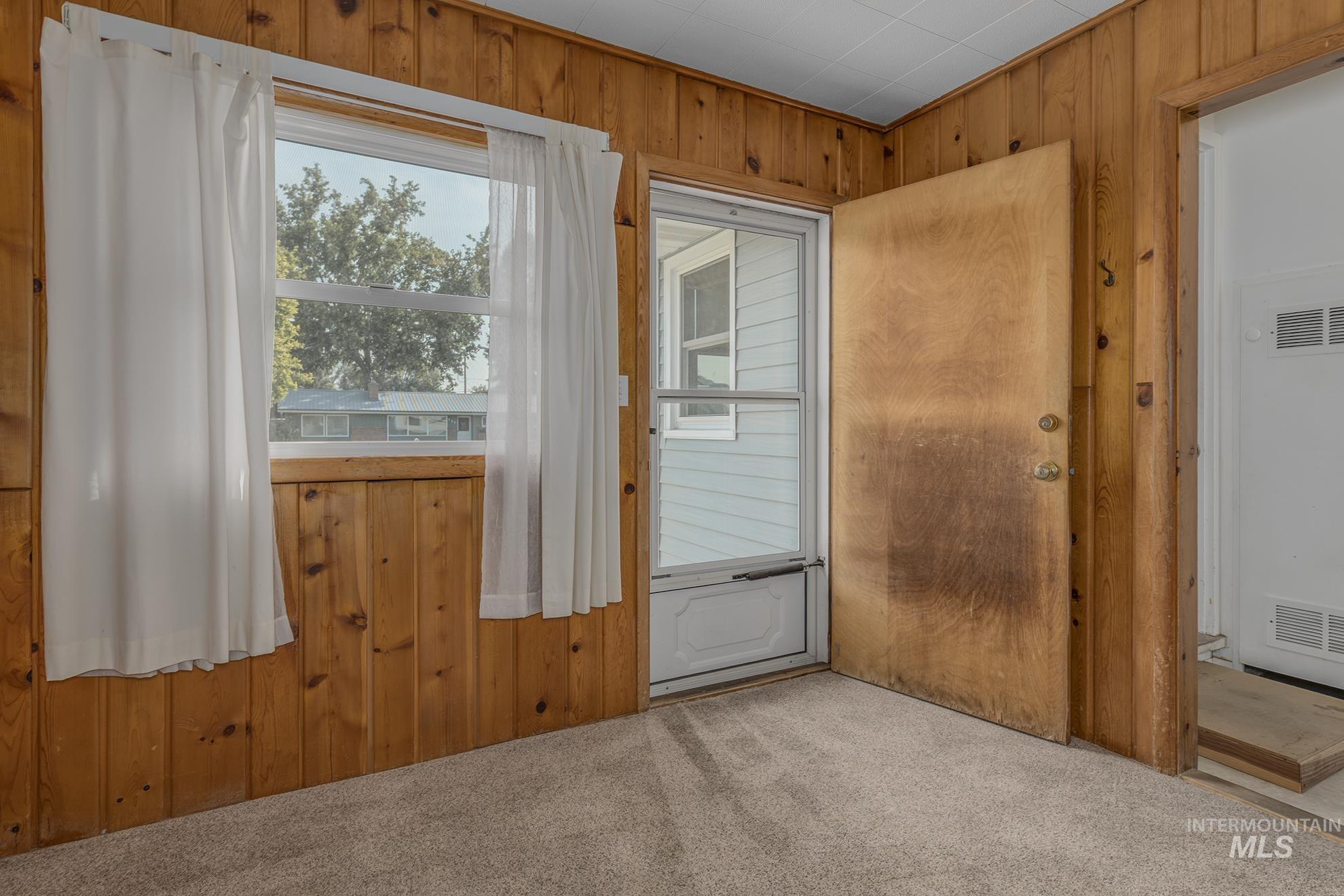 Doorway featuring wood walls, carpet, and a heating unit
