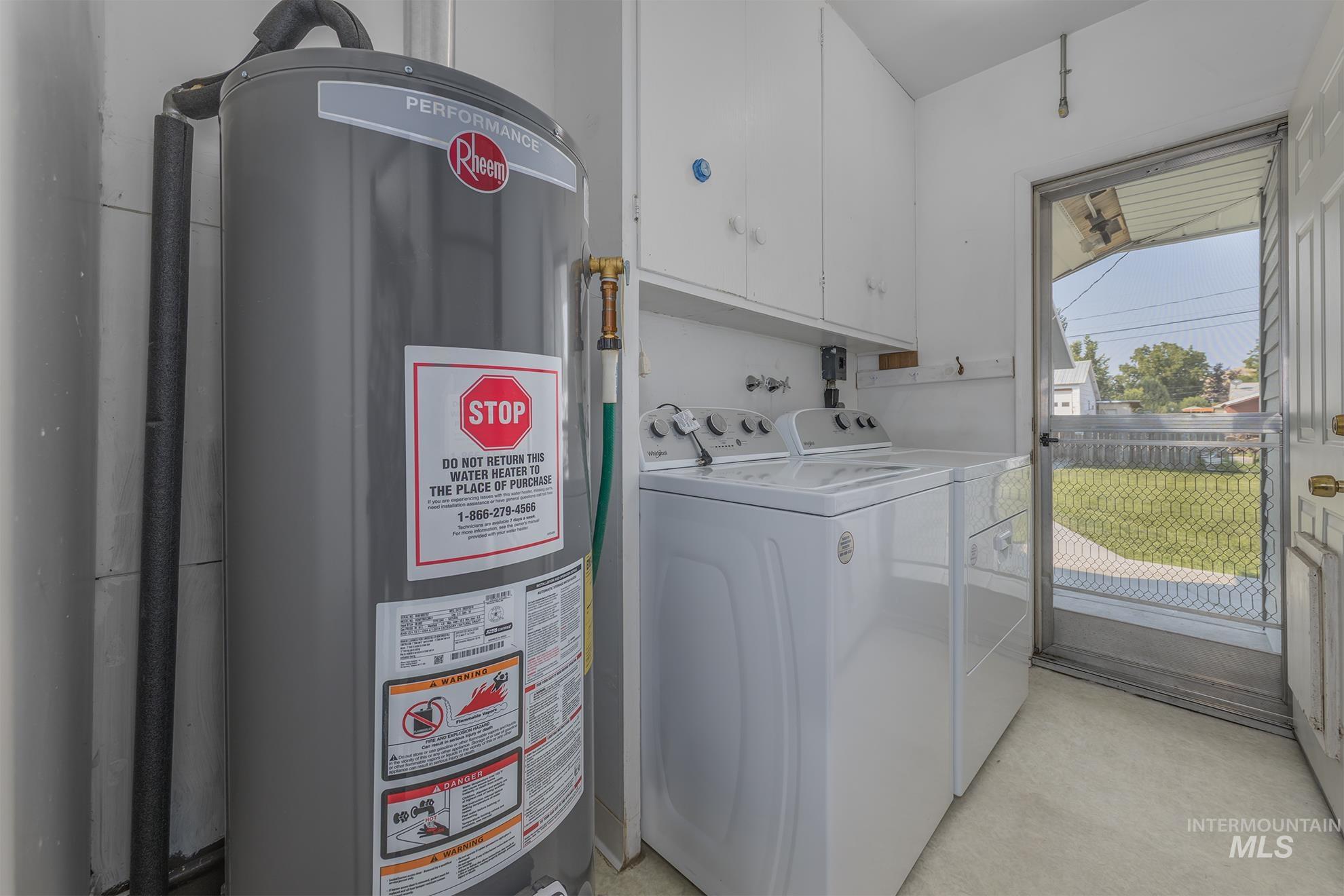 Washroom with gas water heater, cabinet space, and separate washer and dryer