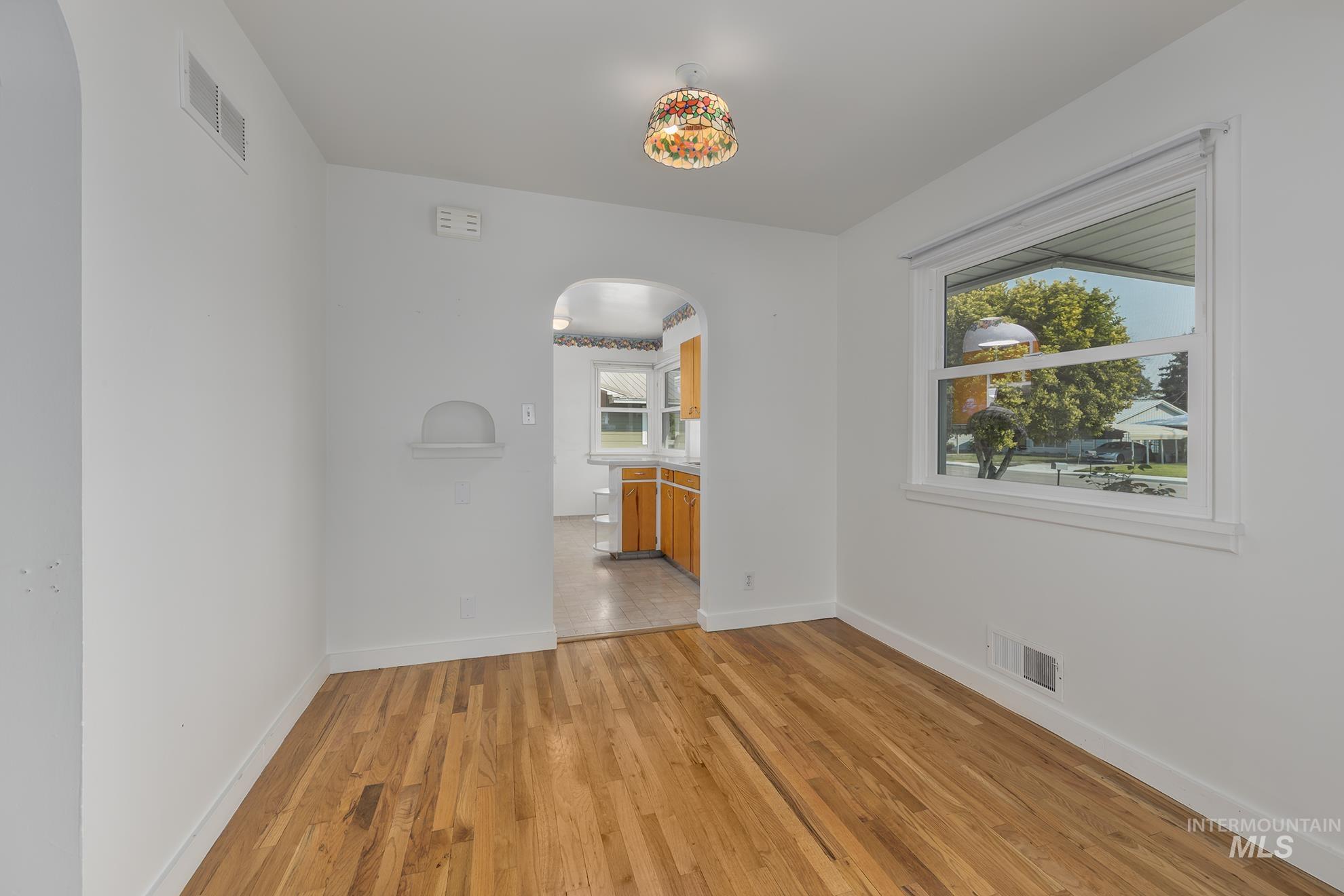 Unfurnished room with arched walkways and light wood-type flooring