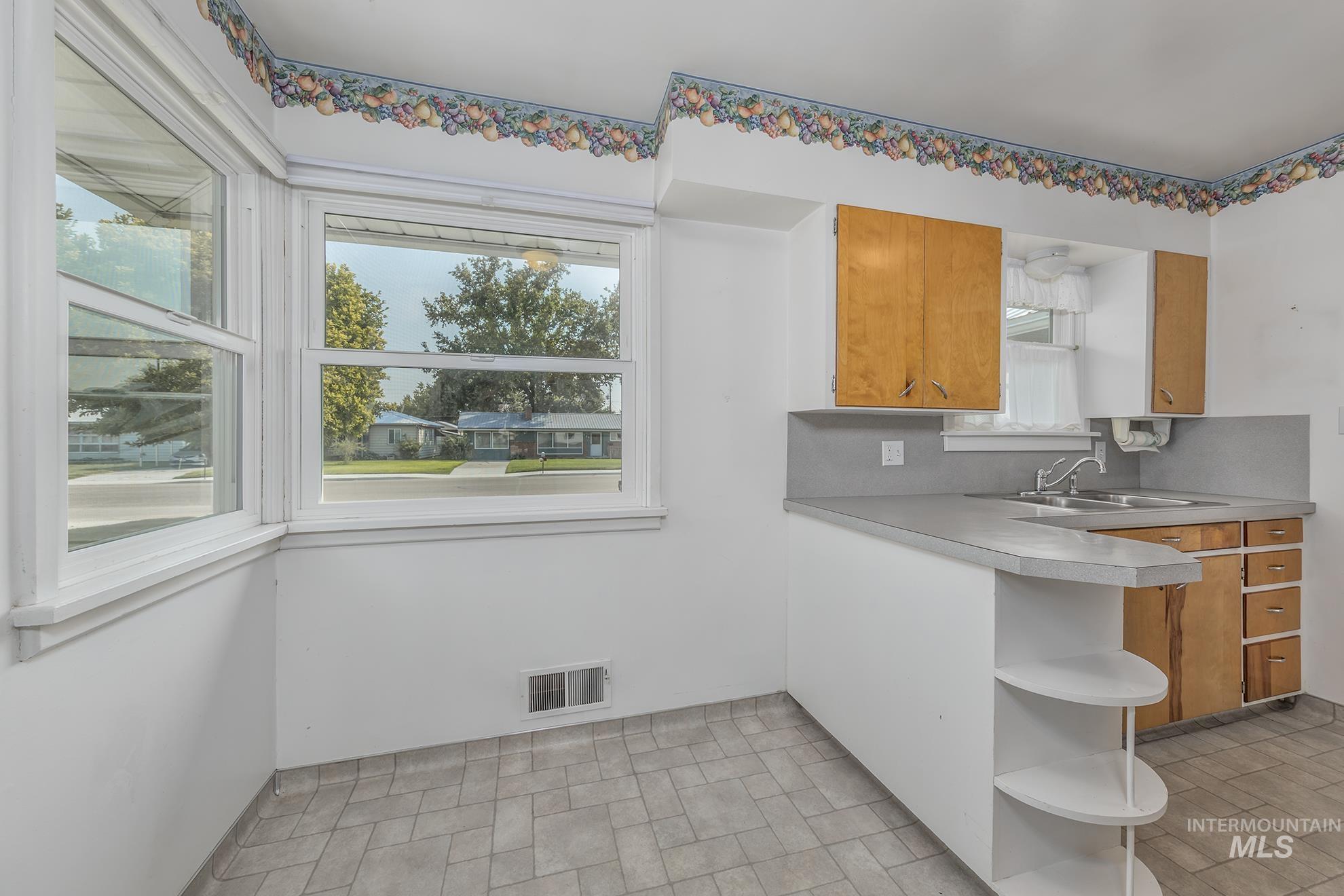 Kitchen featuring open shelves, a peninsula, brown cabinets, and light countertops