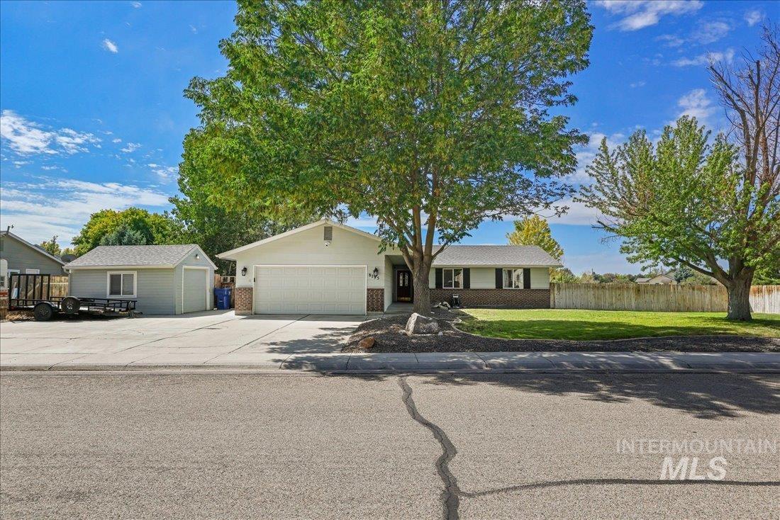Ranch-style home featuring concrete driveway, brick siding, and a garage
