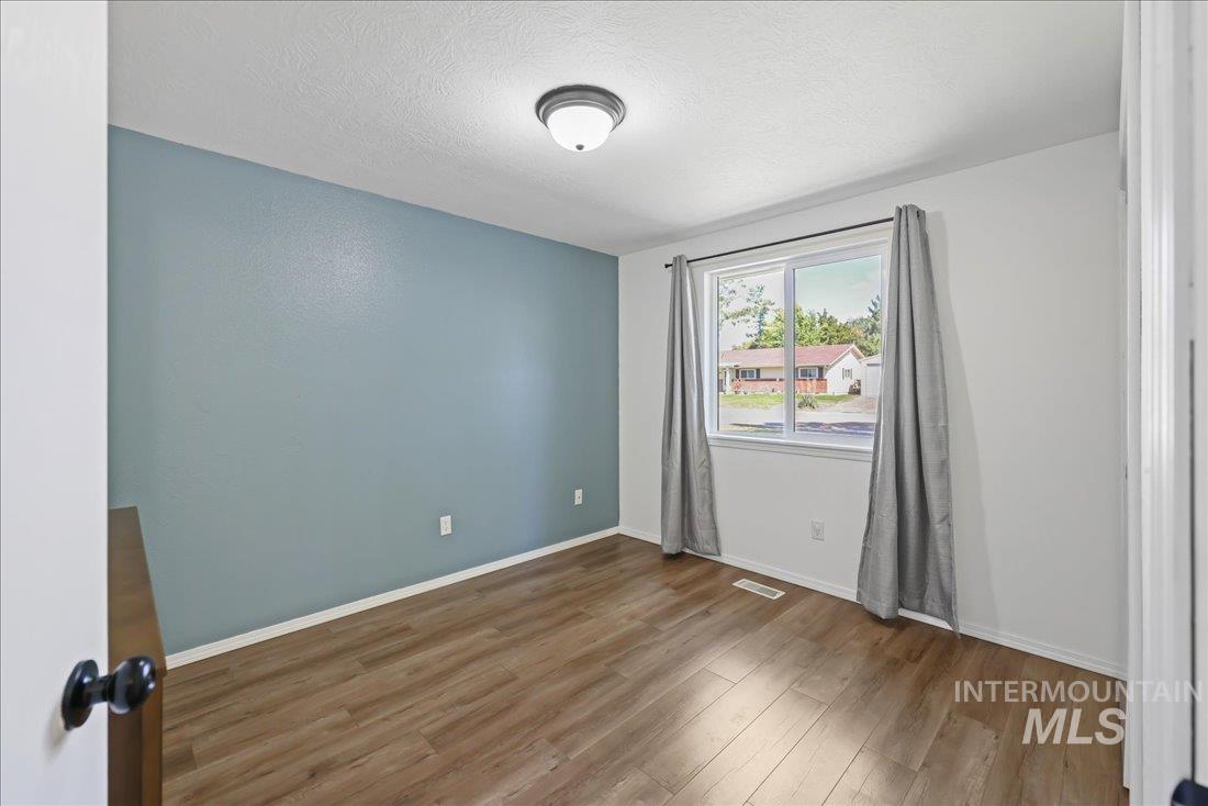 Spare room featuring wood finished floors and a textured ceiling