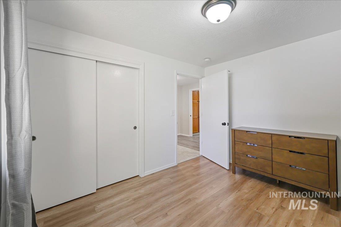 Unfurnished bedroom with light wood-style flooring, a closet, and a textured ceiling