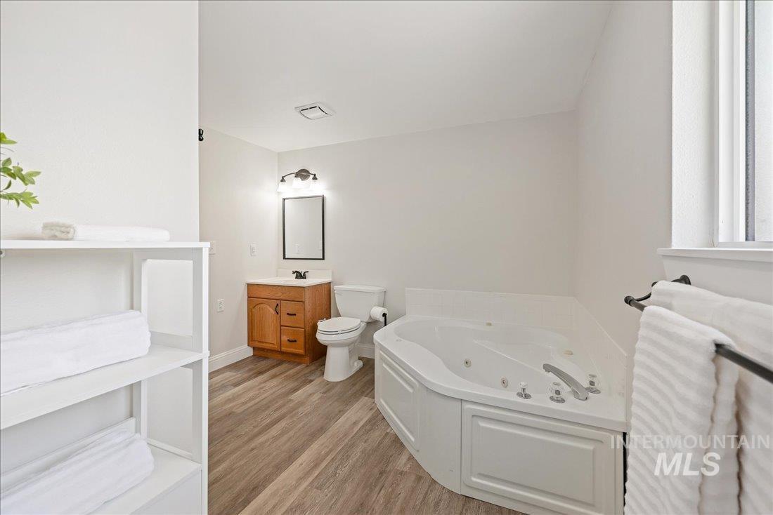 Bathroom featuring vanity, a jetted tub, and light wood-style flooring