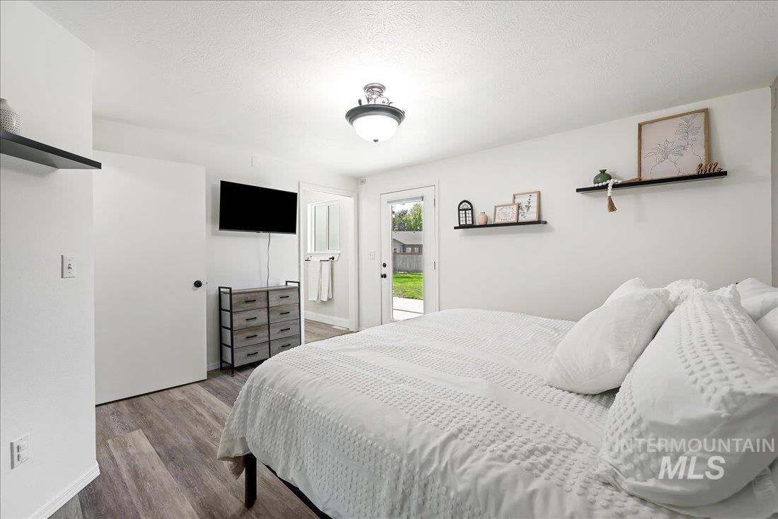 Bedroom with wood finished floors, a textured ceiling, and access to outside