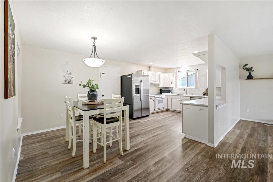 Kitchen featuring appliances with stainless steel finishes, white cabinetry, light countertops, and dark wood-type flooring