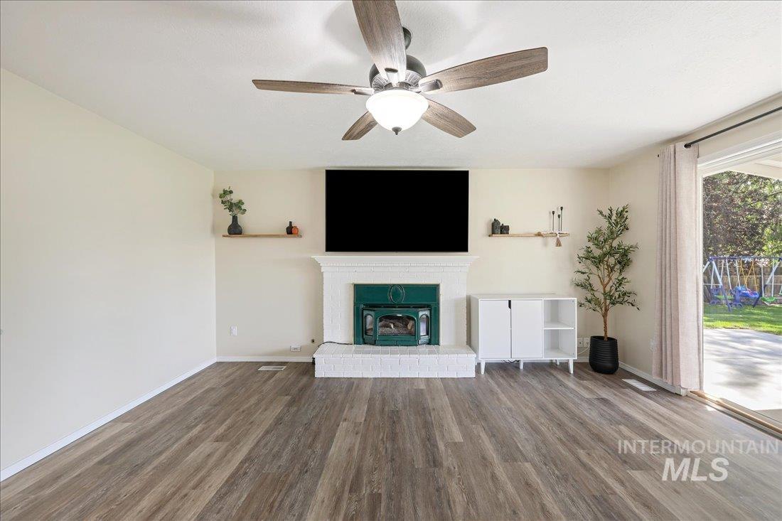 Unfurnished living room with wood finished floors, ceiling fan, and a fireplace