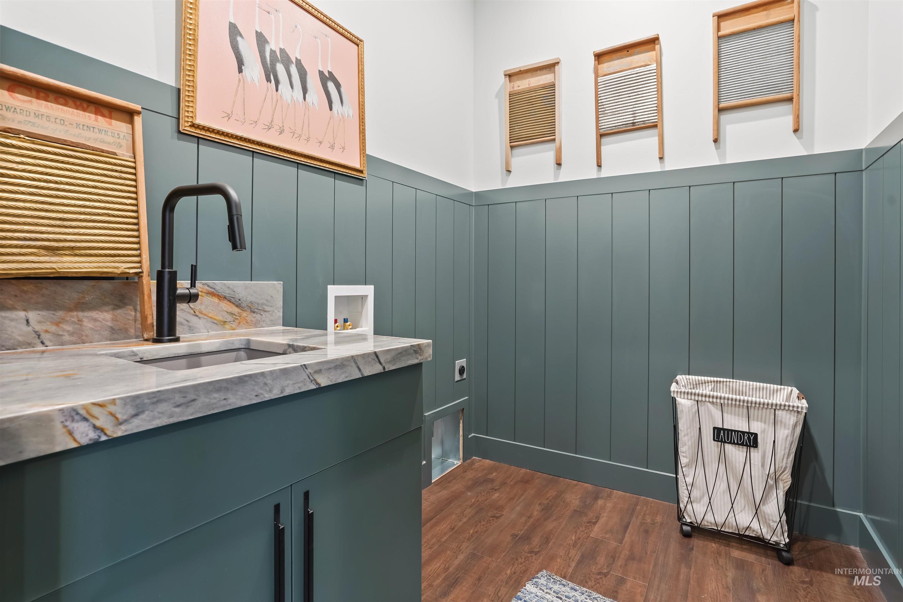 Washroom featuring dark wood-style floors, cabinet space, hookup for a washing machine, electric dryer hookup, and a wainscoted wall