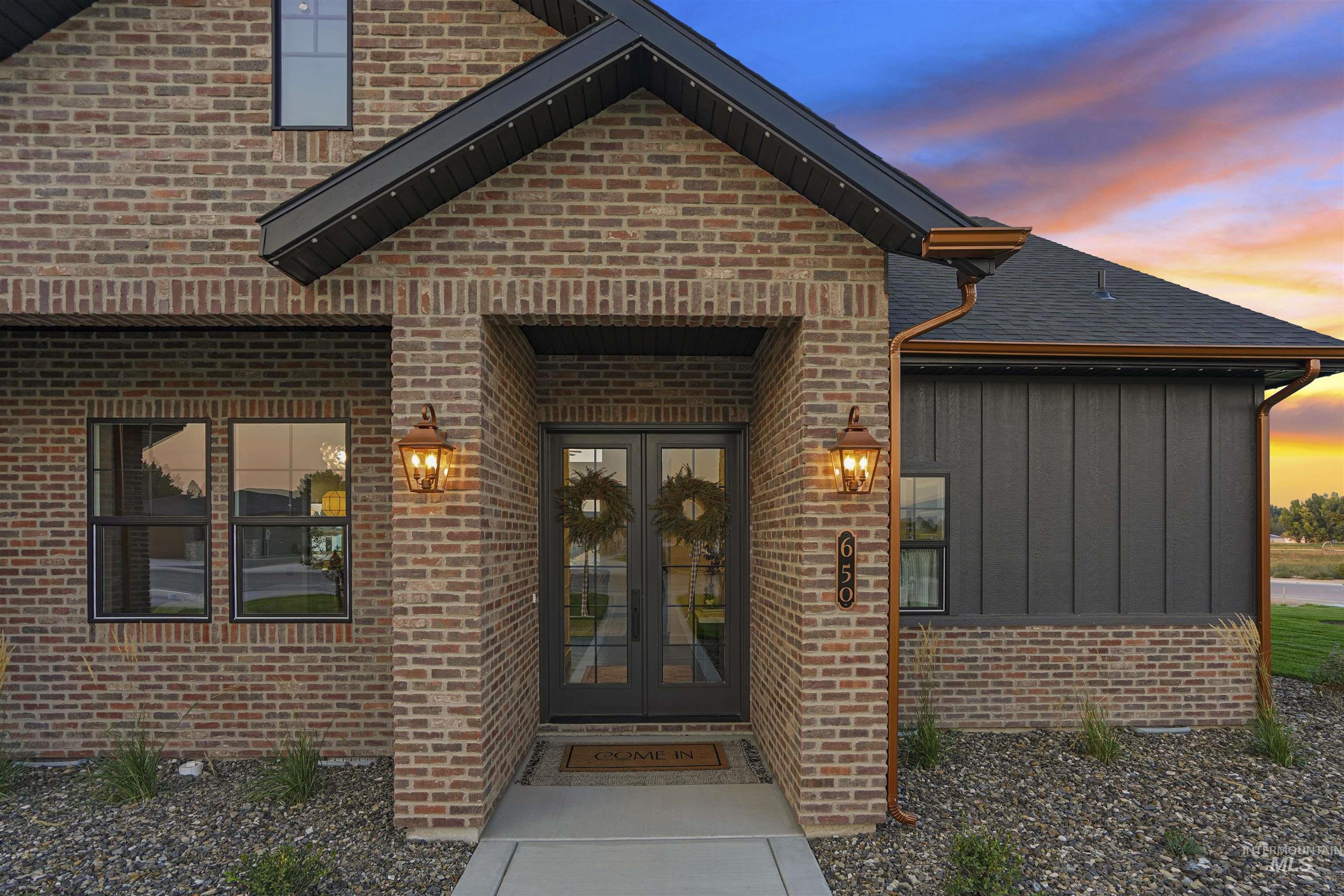 Exterior entry at dusk featuring board and batten siding, french doors, and brick siding