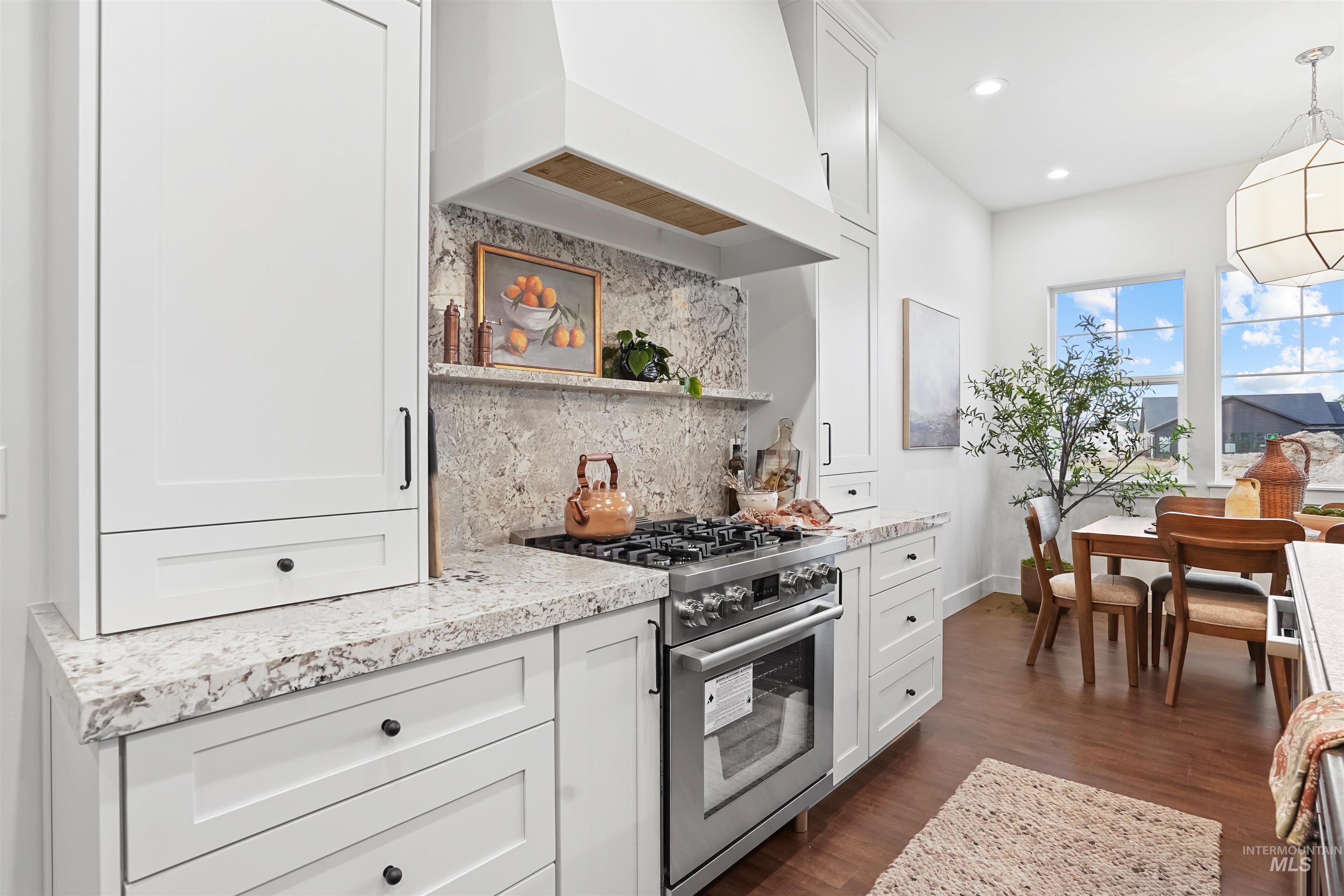 Kitchen with open shelves, tasteful backsplash, stainless steel gas range oven, white cabinets, and hanging light fixtures