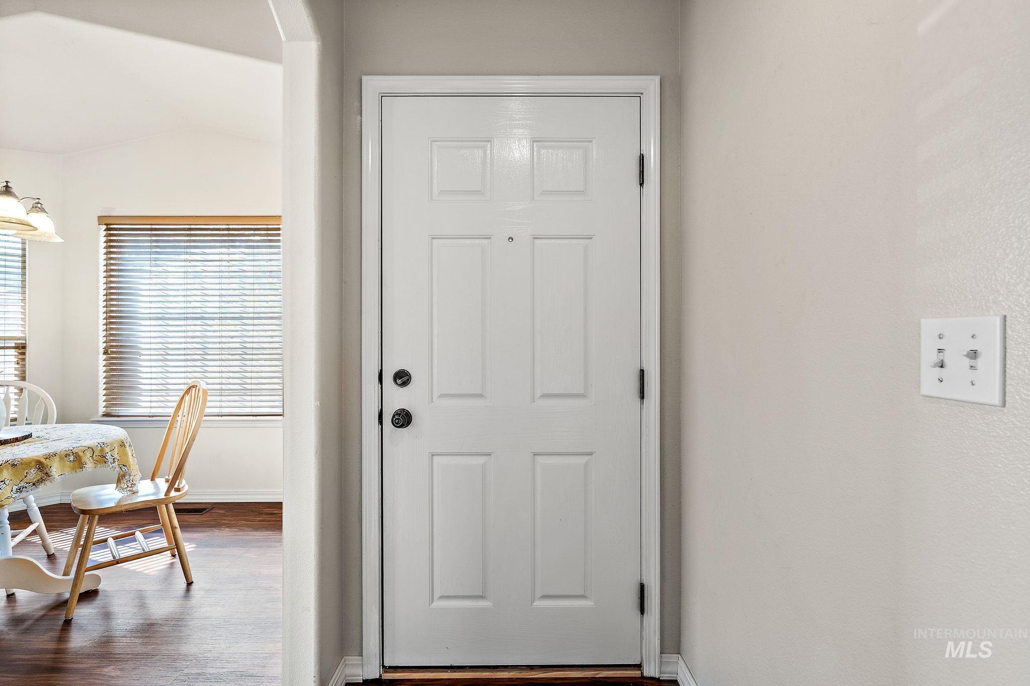 Foyer with dark wood finished floors and vaulted ceiling