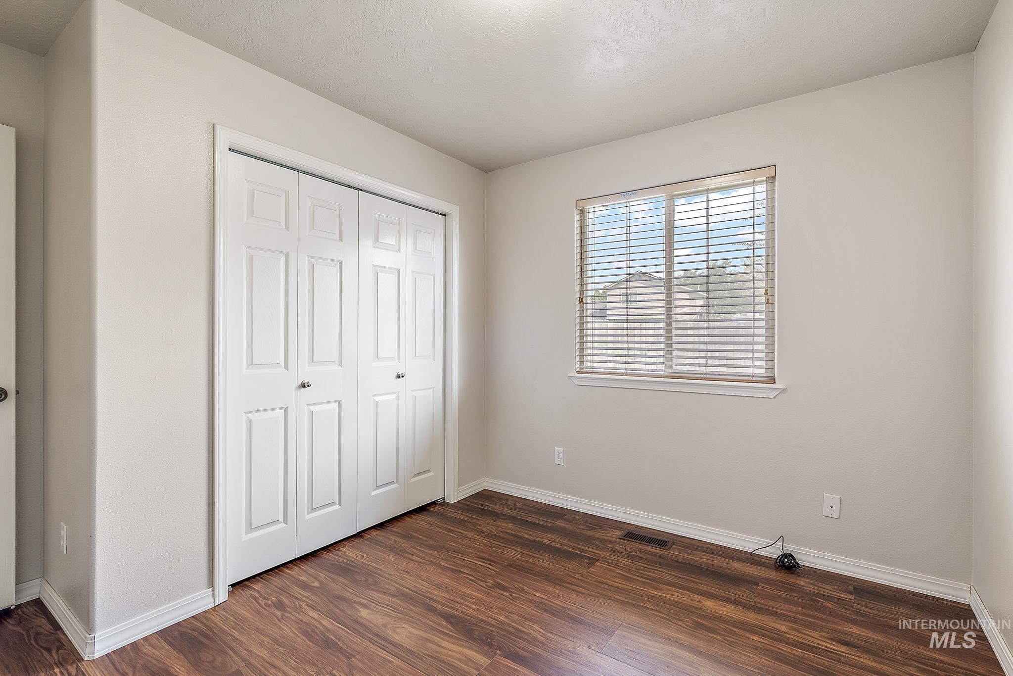 Unfurnished bedroom with dark wood-style flooring and a closet