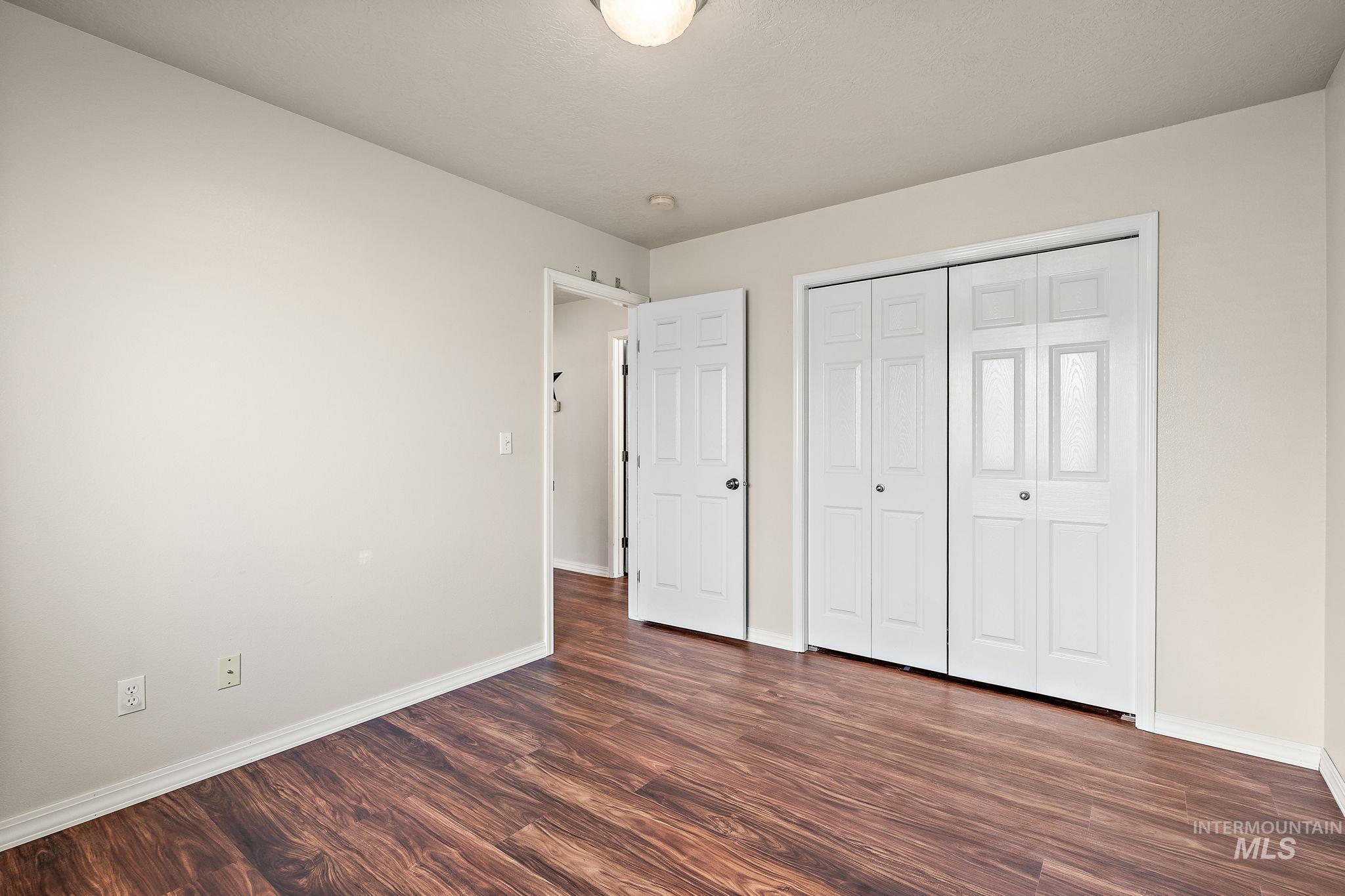 Unfurnished bedroom featuring dark wood-type flooring and a closet