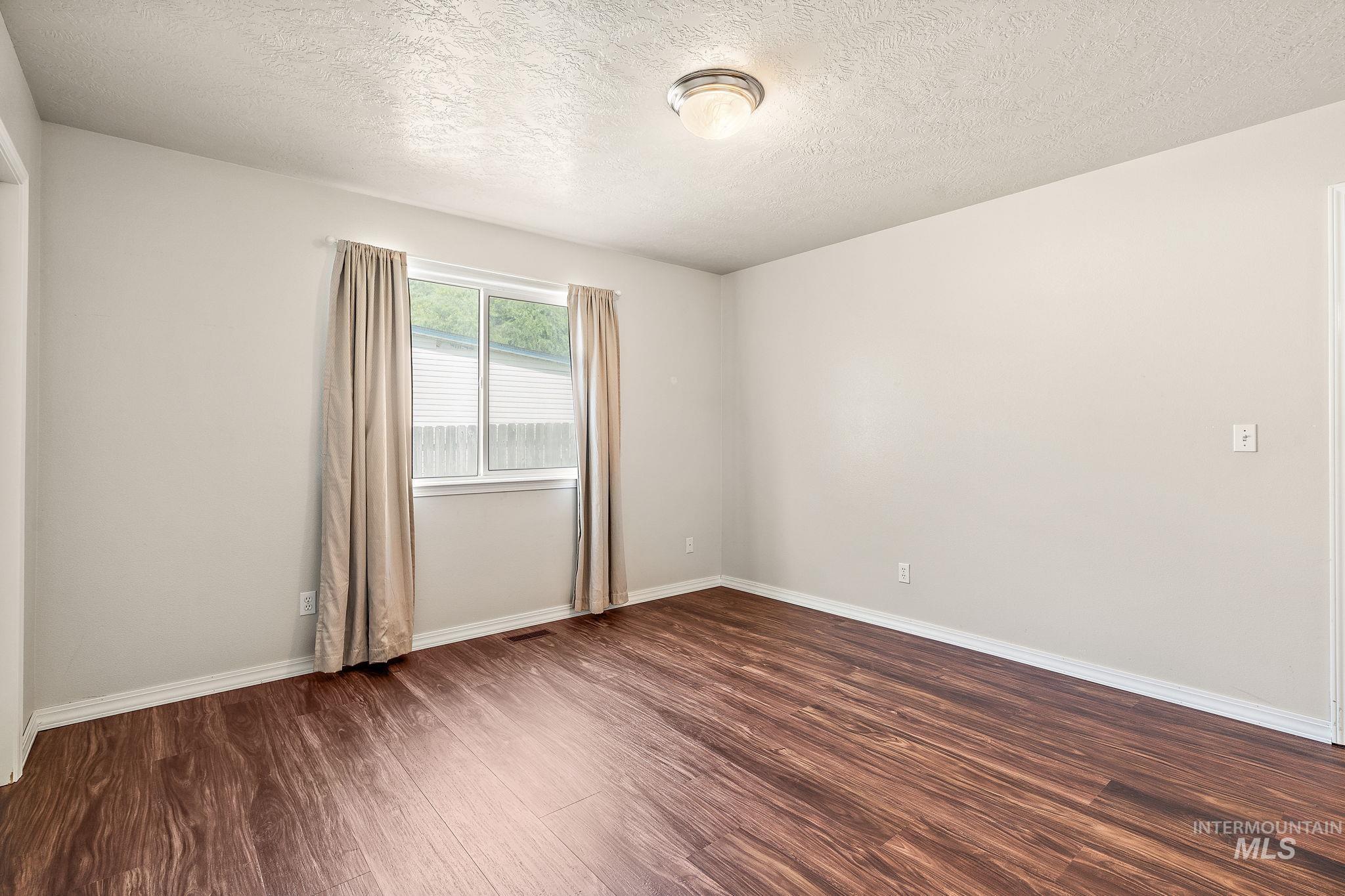 Empty room with dark wood-style floors and a textured ceiling