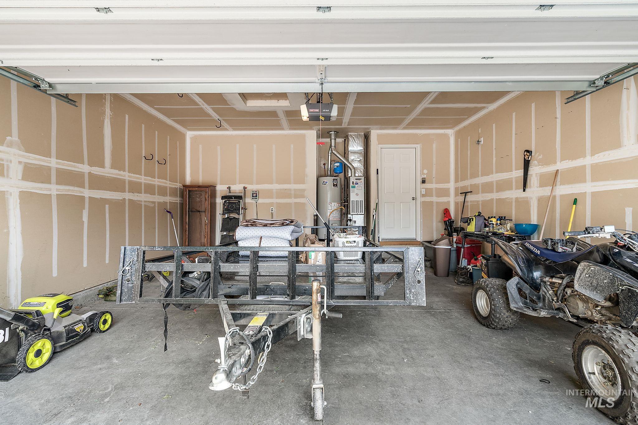 Garage with heating unit, water heater, and a garage door opener