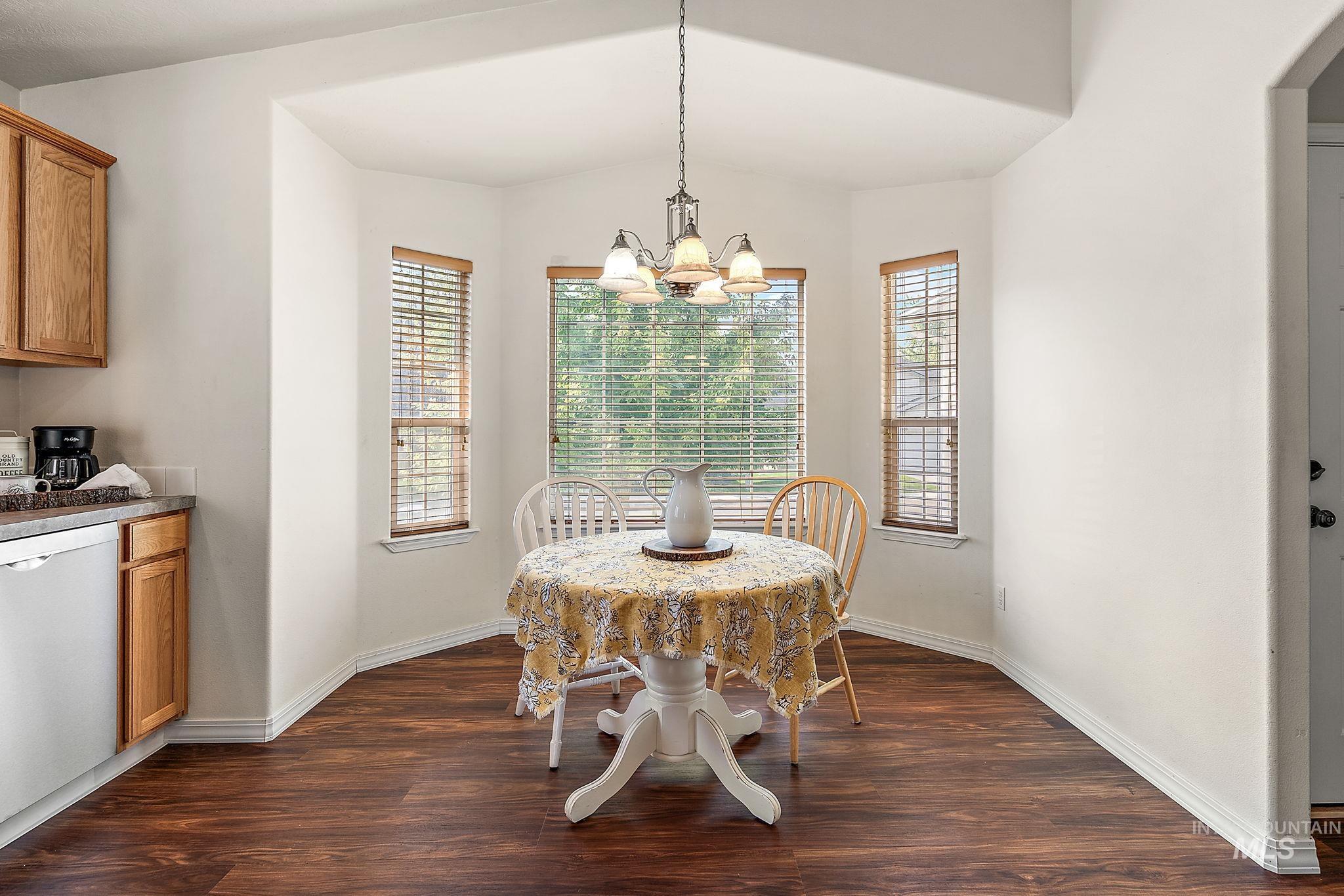 Dining room with dark wood-style floors, healthy amount of natural light, and a chandelier