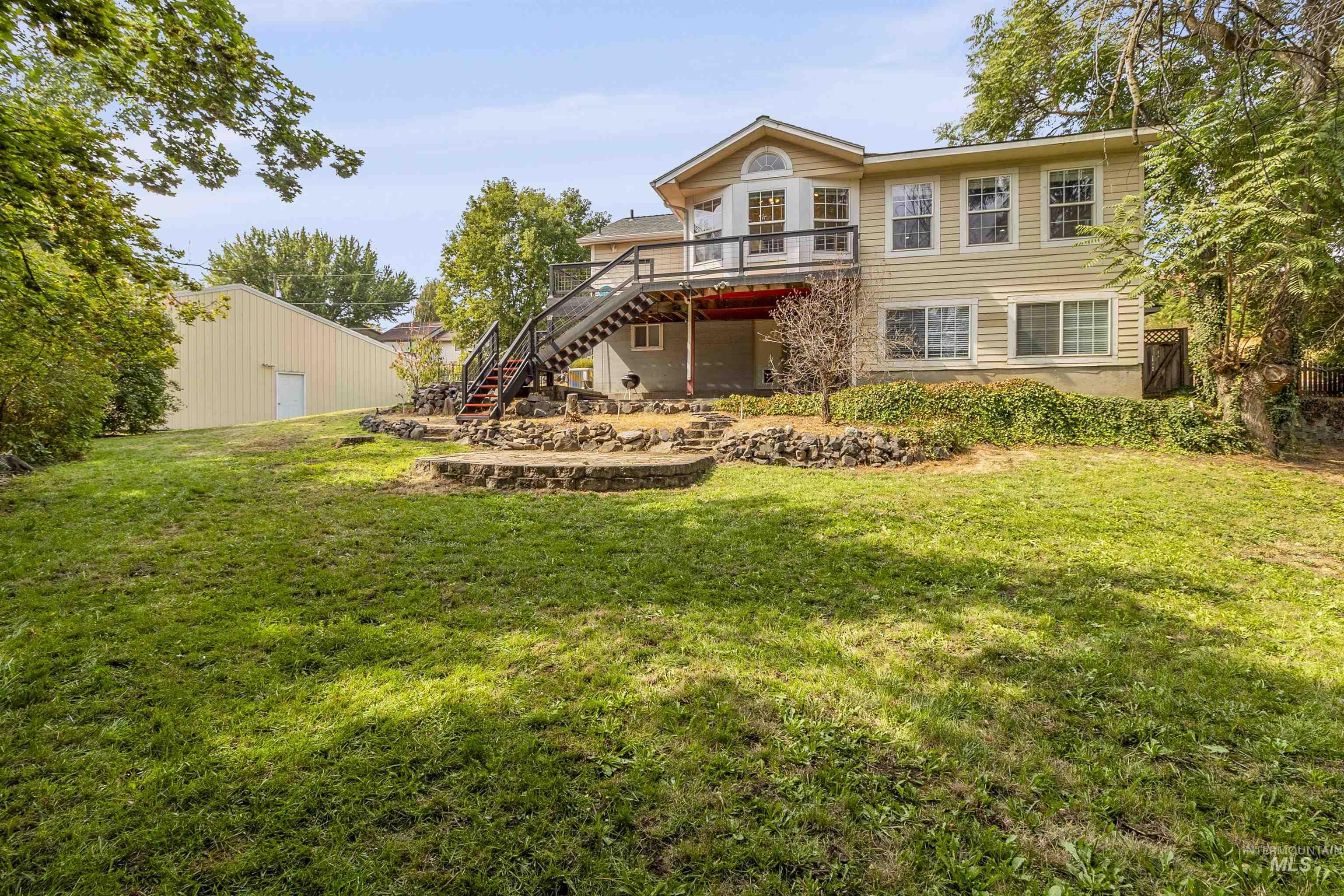 Back of property with stairs, a yard, and a deck