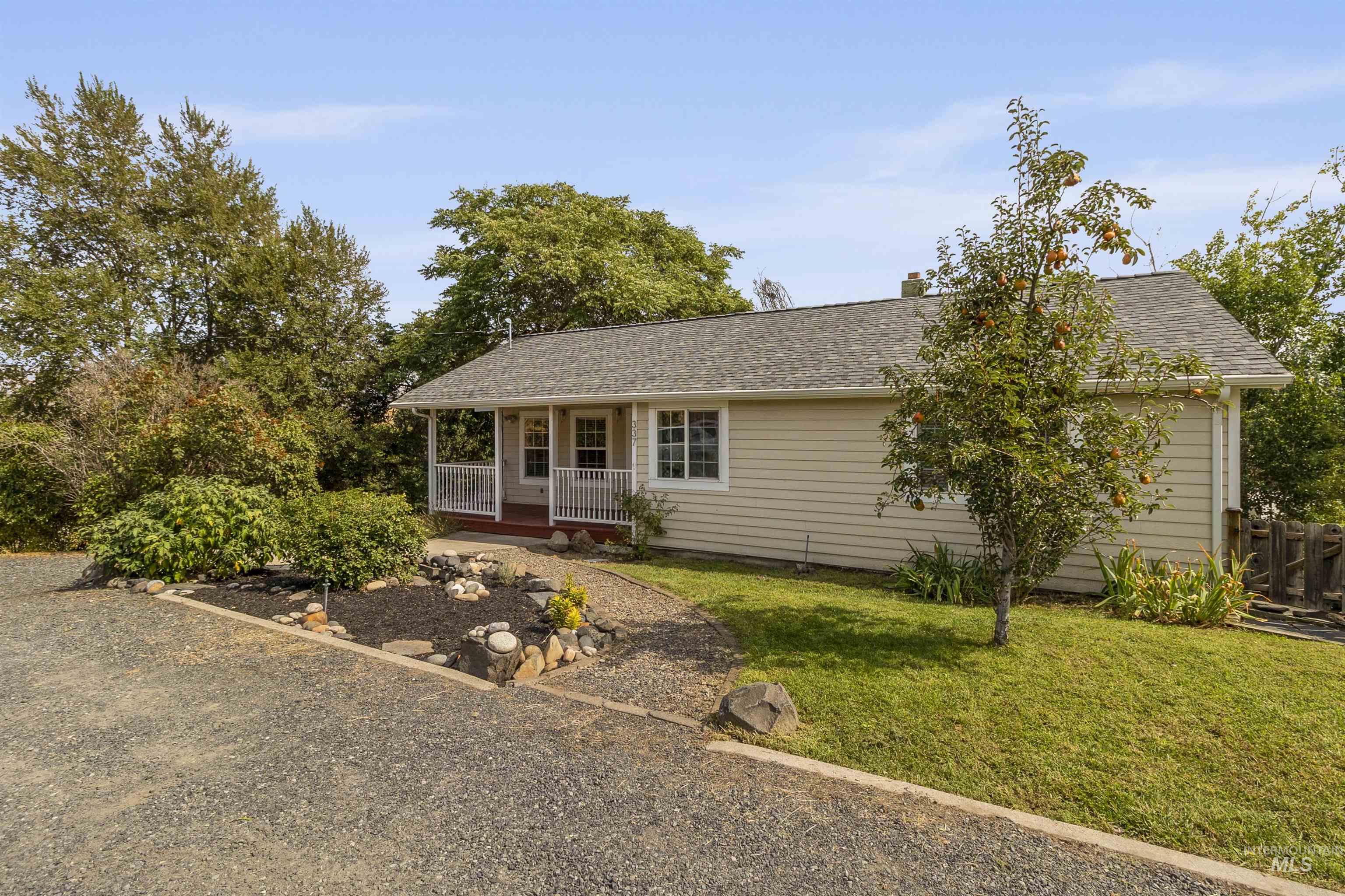 Ranch-style house featuring covered porch, a front lawn, roof with shingles, and a chimney