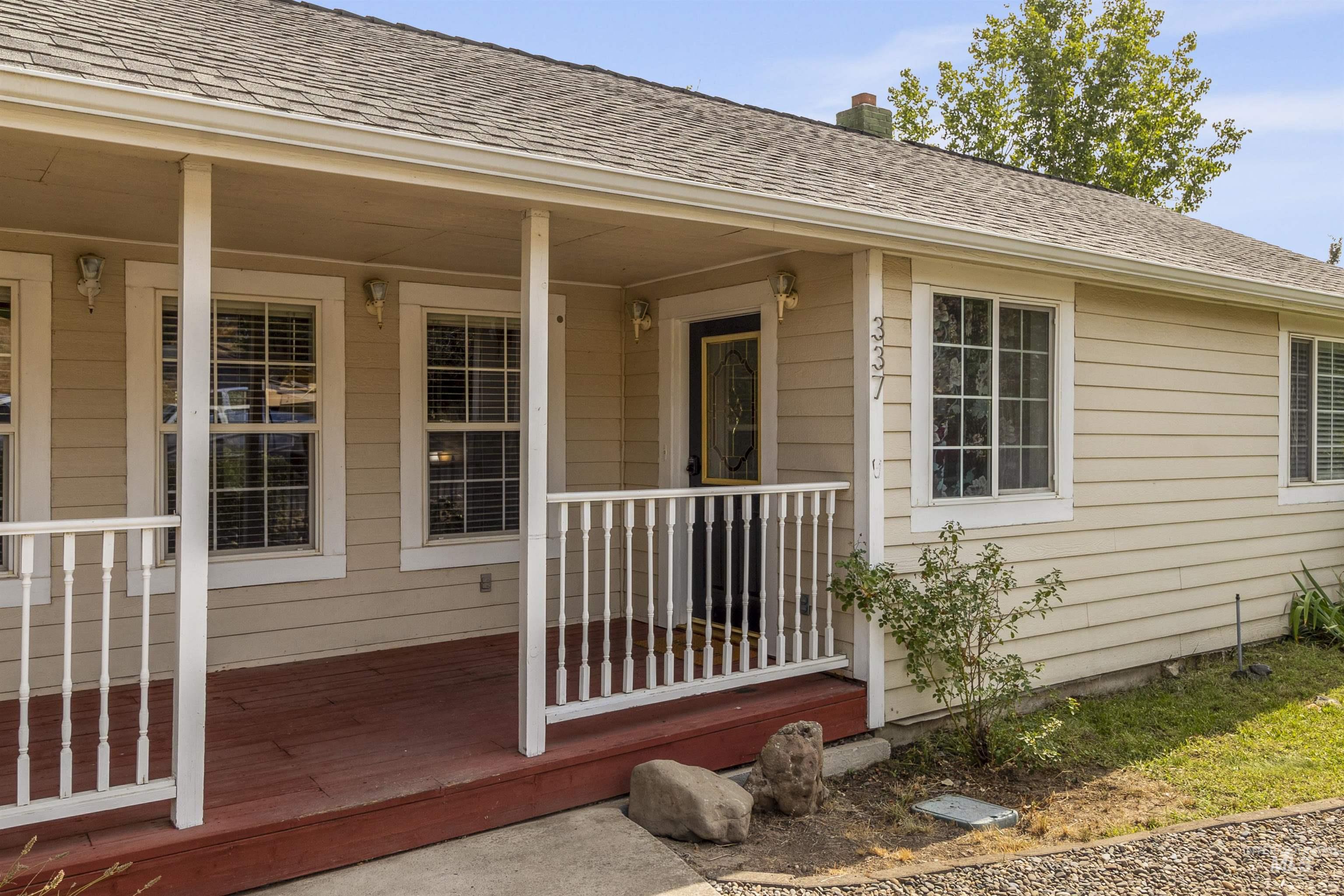 View of exterior entry featuring a shingled roof, a chimney, and a porch