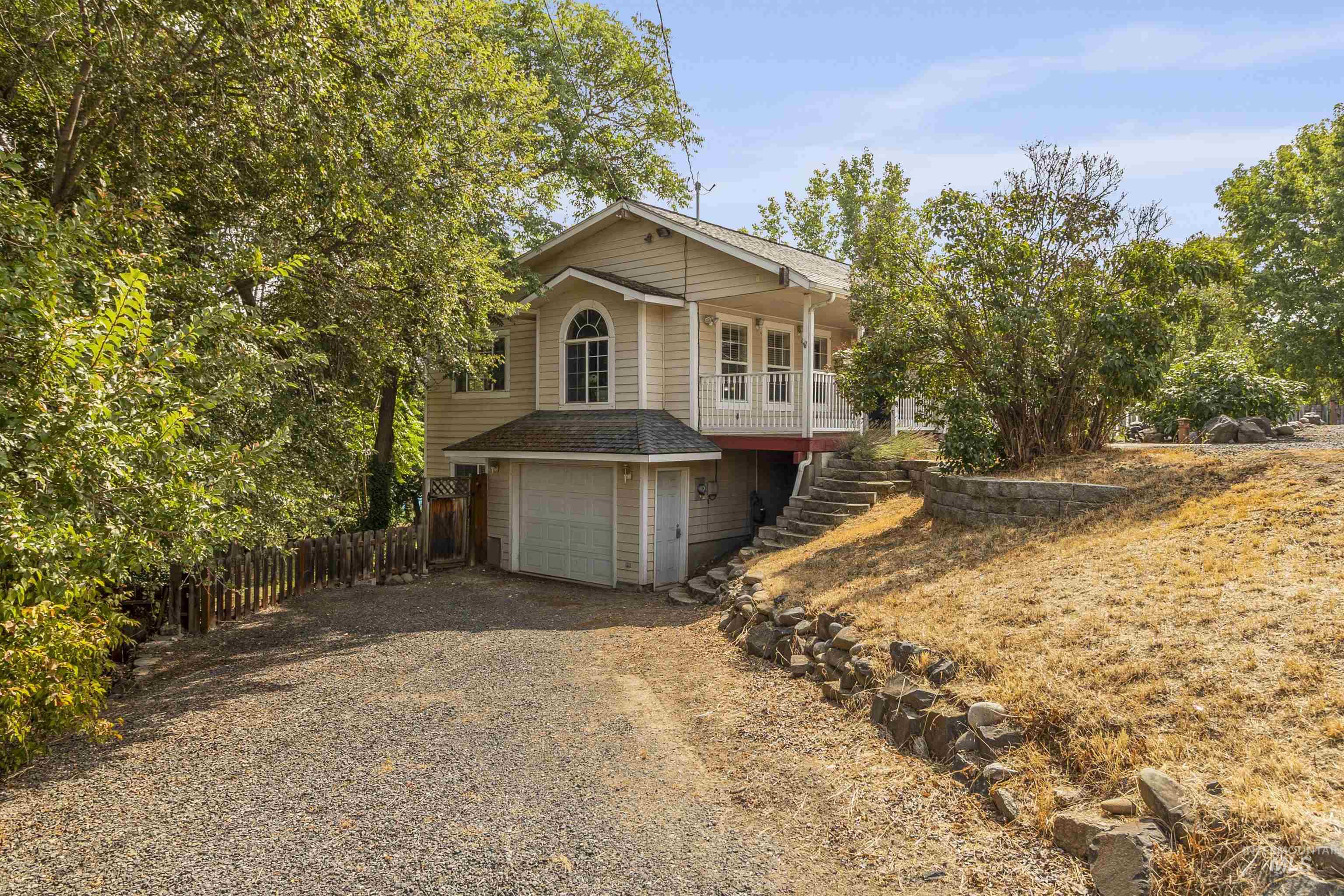 View of front facade with driveway, an attached garage, stairs, and a shingled roof
