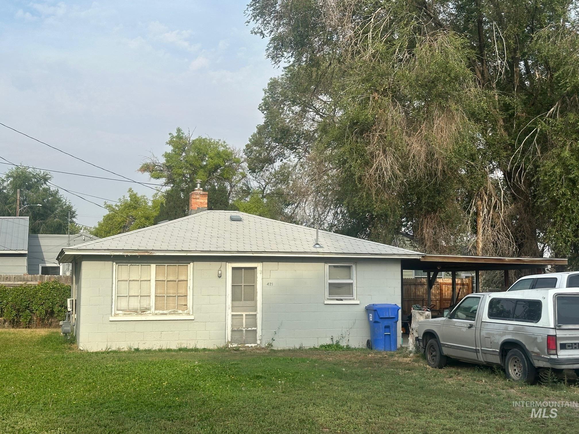Back of property featuring concrete block siding, a yard, a shingled roof, and a chimney