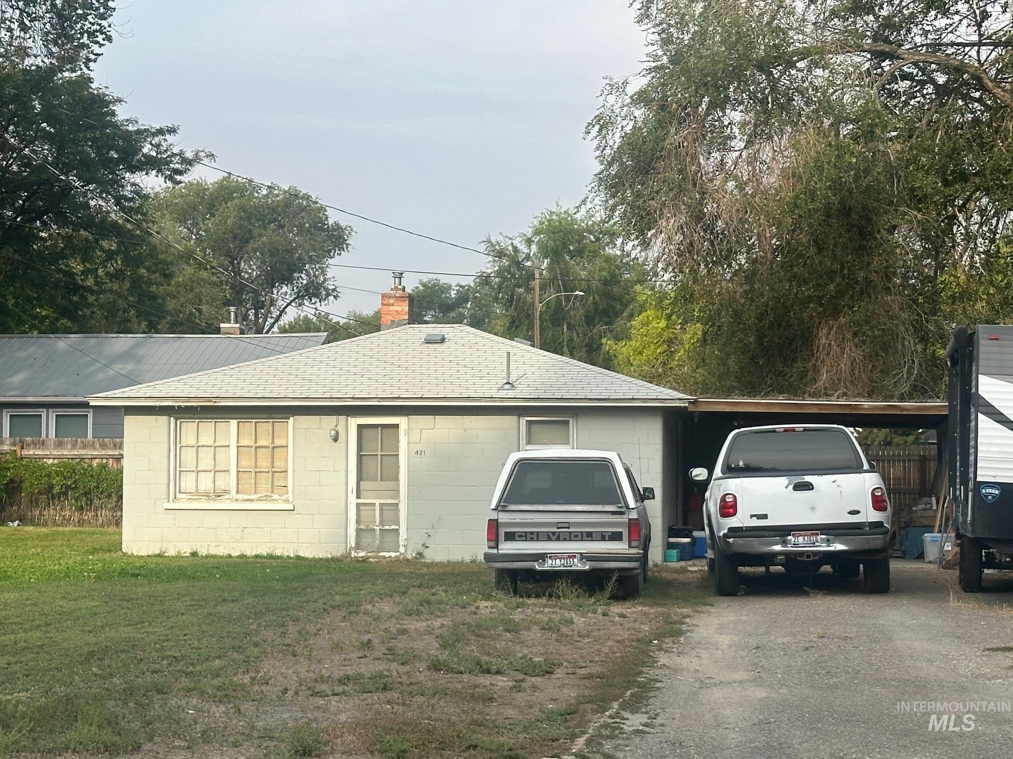 Ranch-style home with a chimney, concrete block siding, driveway, and roof with shingles