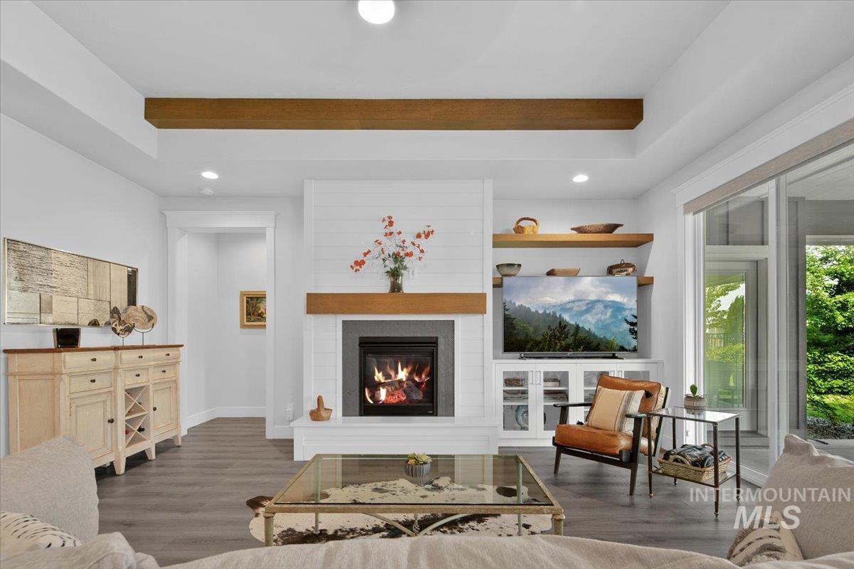 Living room with a large fireplace, recessed lighting, wood finished floors, and beam ceiling