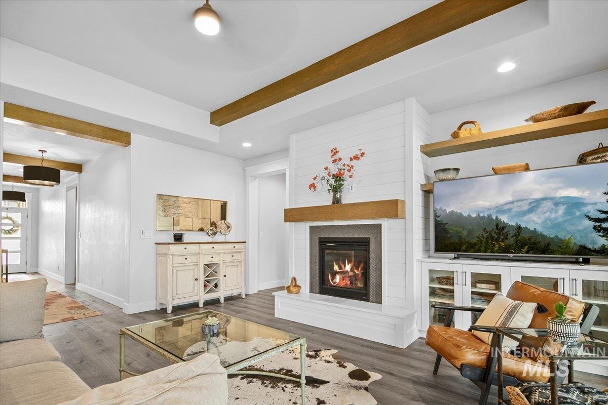 Living room featuring beamed ceiling, recessed lighting, a large fireplace, and wood finished floors