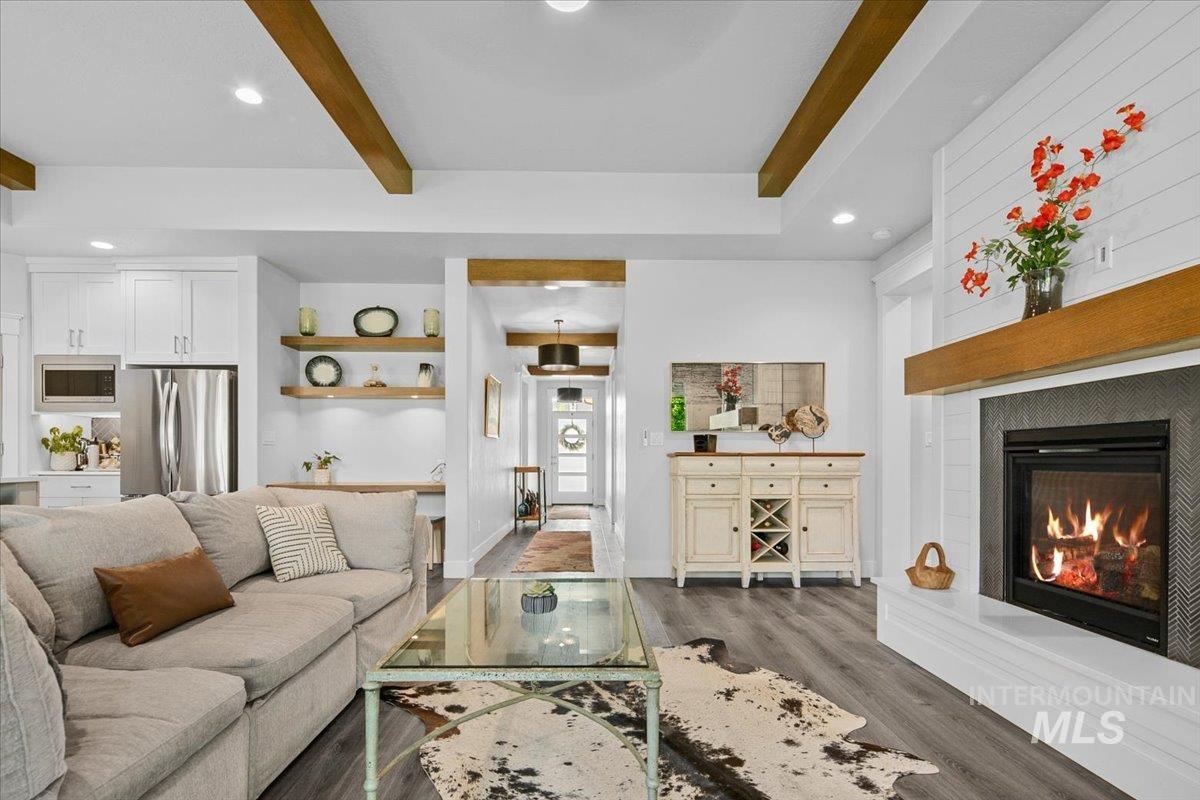 Living room with recessed lighting, beam ceiling, dark wood-type flooring, and a glass covered fireplace