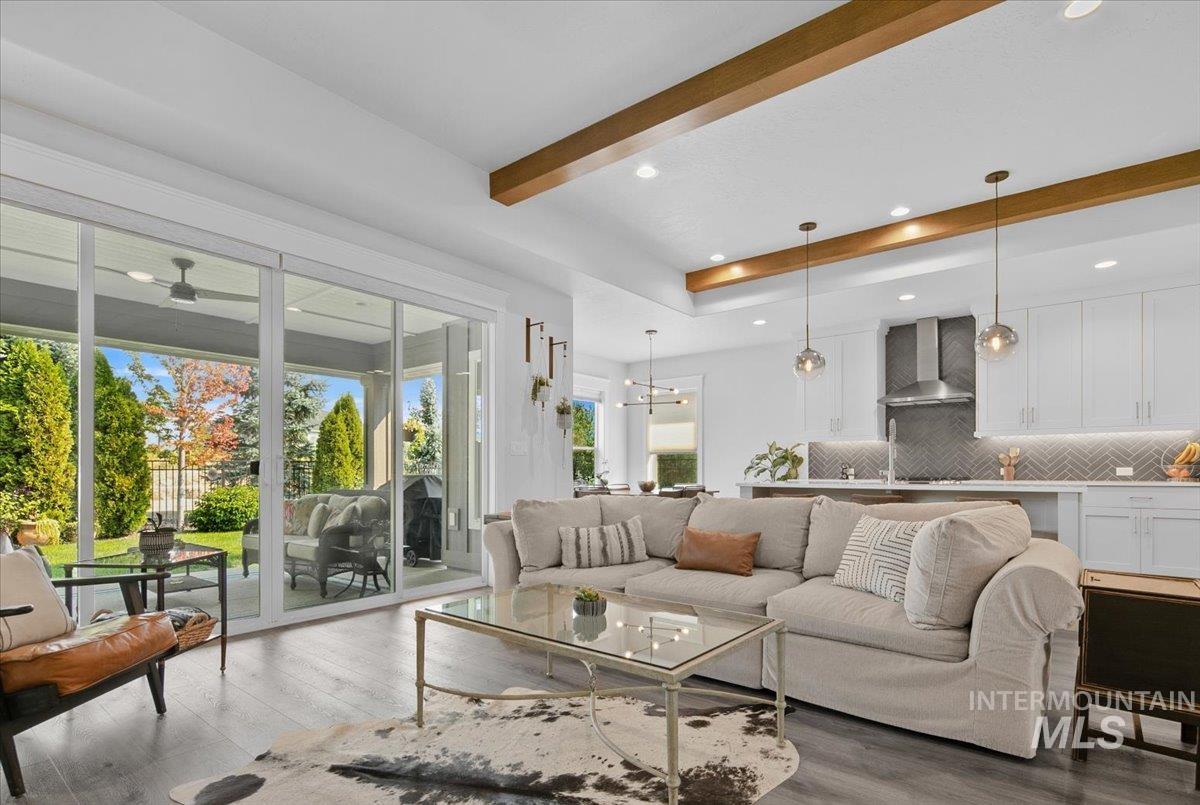 Living area with wood finished floors, beam ceiling, recessed lighting, and a chandelier