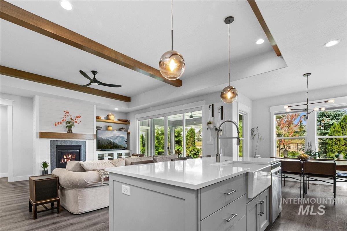 Kitchen with recessed lighting, decorative light fixtures, dark wood-style flooring, gray cabinetry, and a glass covered fireplace