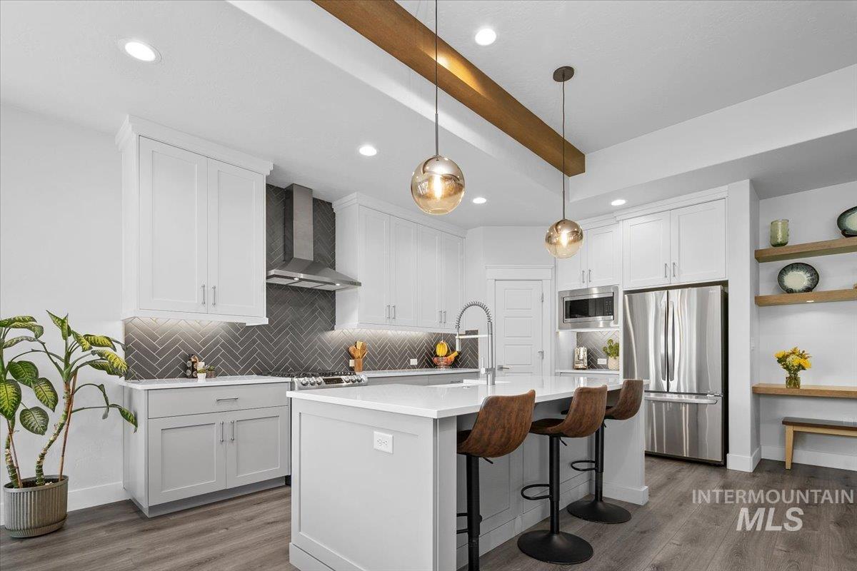 Kitchen featuring a kitchen breakfast bar, tasteful backsplash, appliances with stainless steel finishes, pendant lighting, and recessed lighting