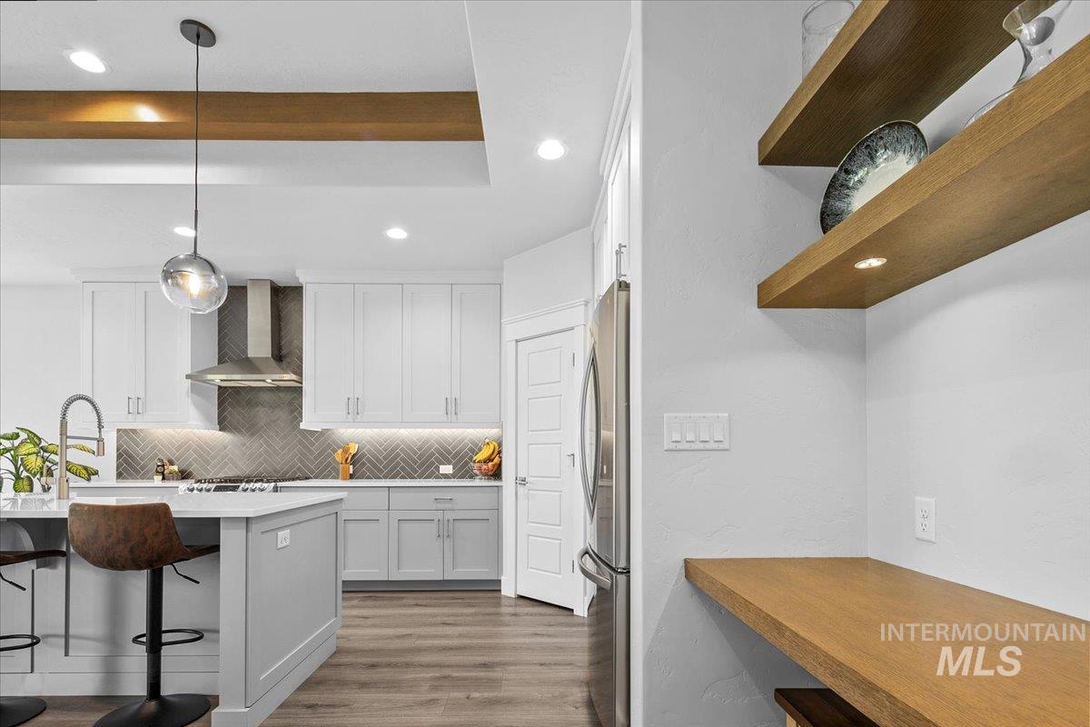 Kitchen featuring tasteful backsplash, decorative light fixtures, recessed lighting, a kitchen bar, and white cabinetry