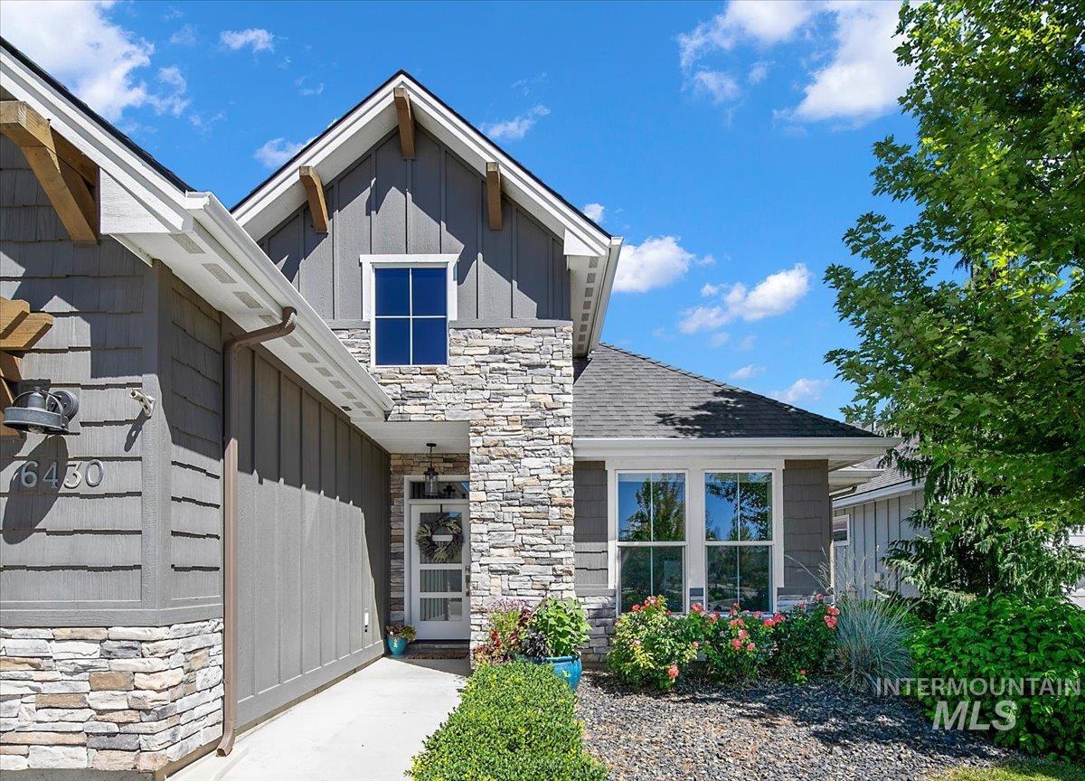 Entrance to property with stone siding, board and batten siding, and a shingled roof