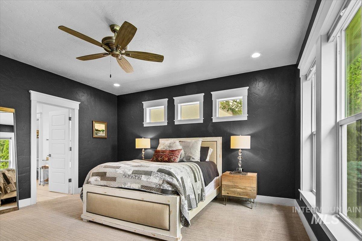 Bedroom with ceiling fan, a textured ceiling, a textured wall, and light colored carpet
