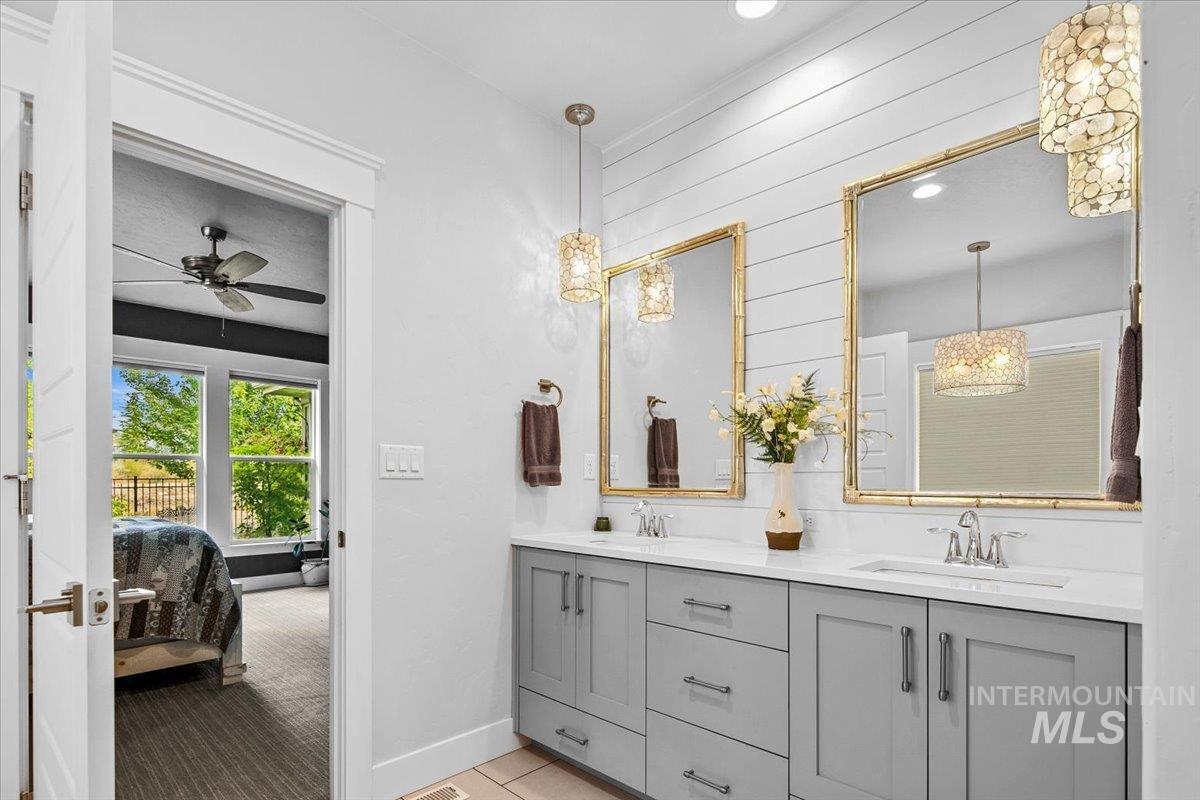 Ensuite bathroom featuring double vanity, a chandelier, a ceiling fan, recessed lighting, and light tile patterned floors