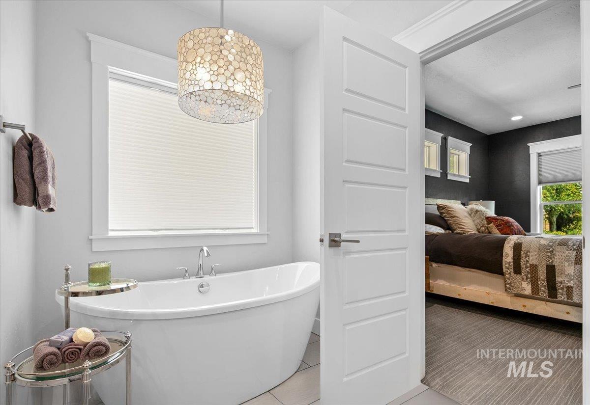 Full bathroom featuring a freestanding tub, light tile patterned floors, and ensuite bath