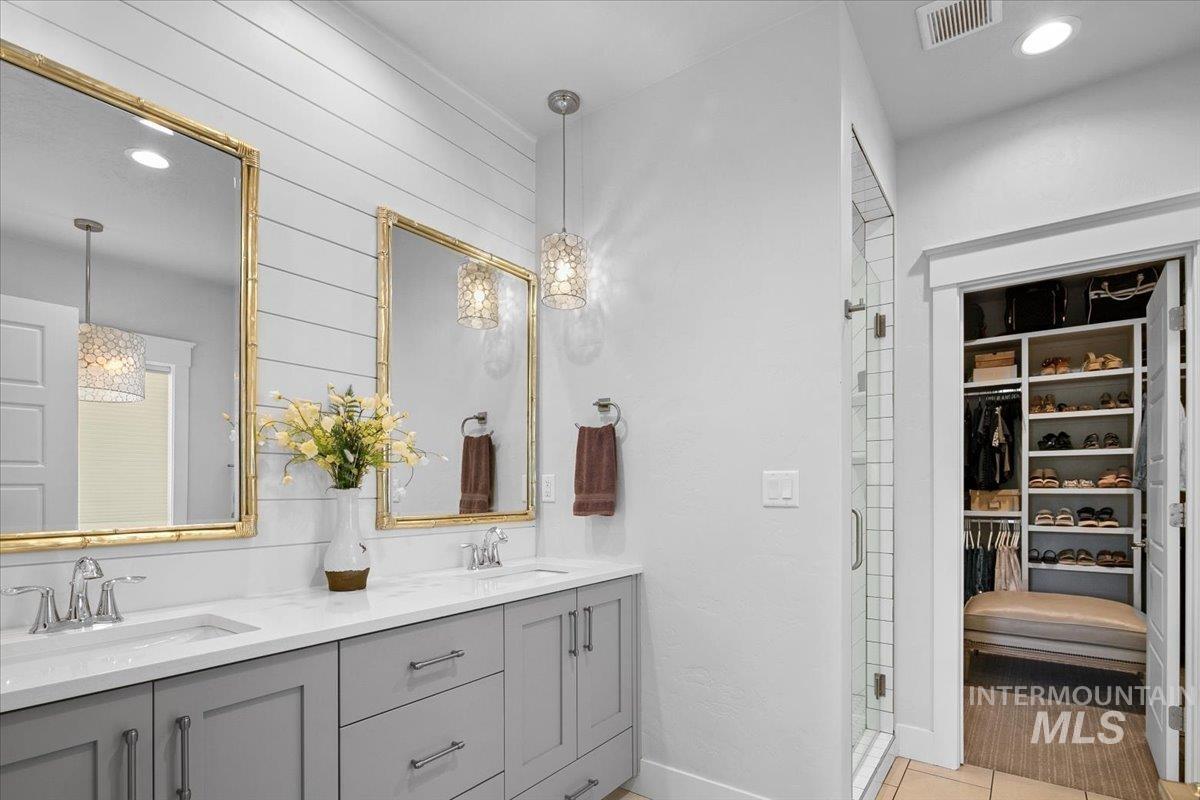 Bathroom featuring recessed lighting, a walk in closet, double vanity, a shower stall, and light tile patterned floors