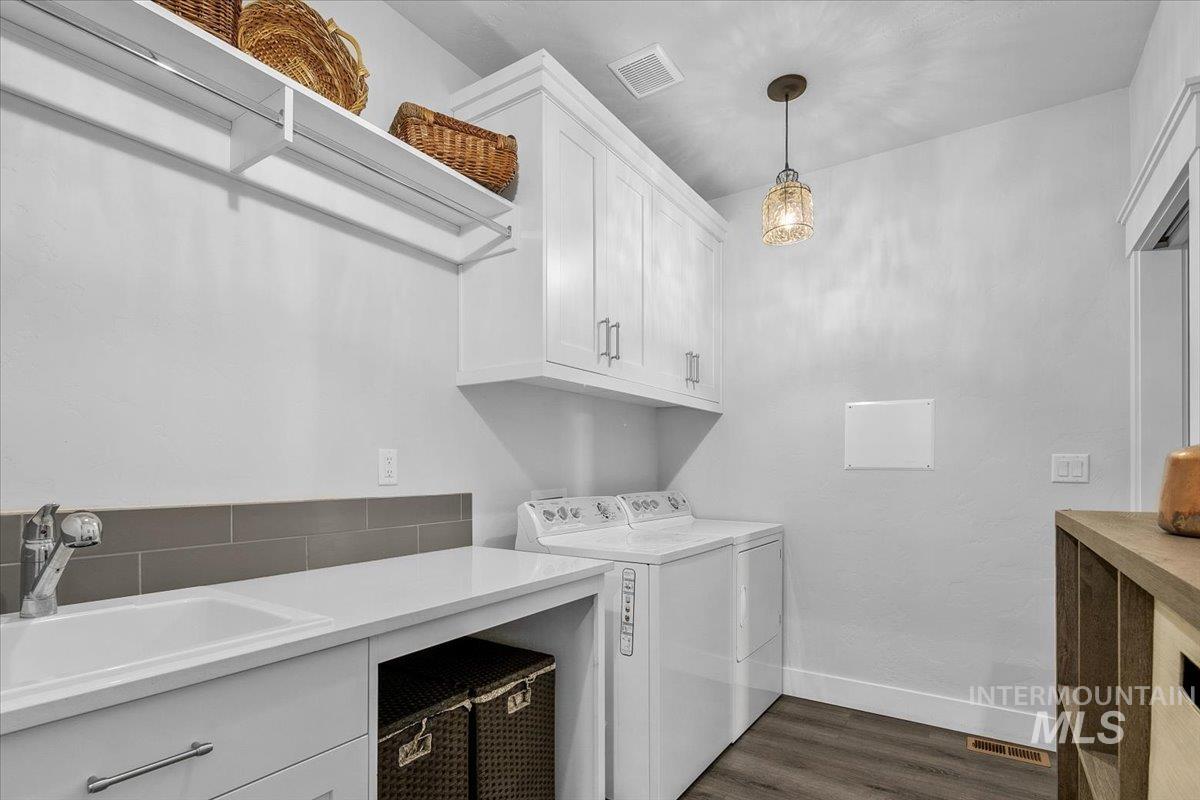 Washroom with dark wood-type flooring, washer and clothes dryer, and cabinet space