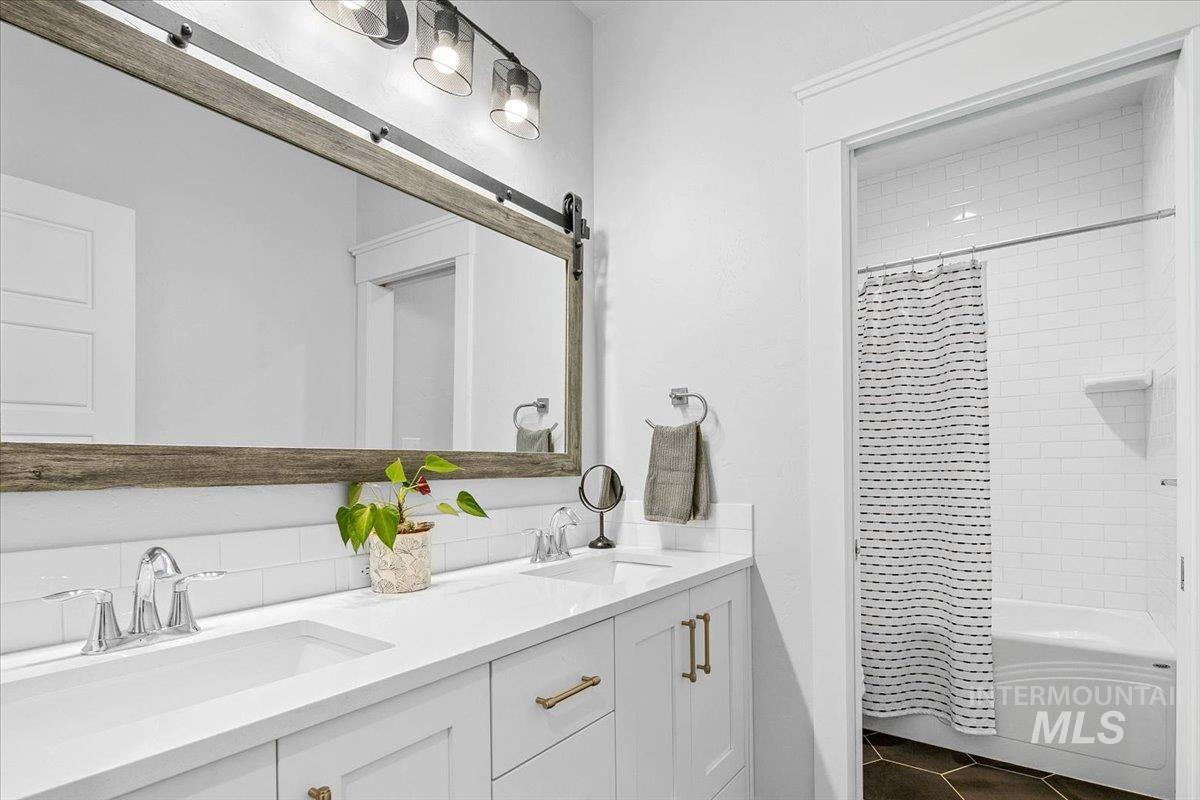 Full bathroom with shower / bath combo, double vanity, and dark tile patterned floors