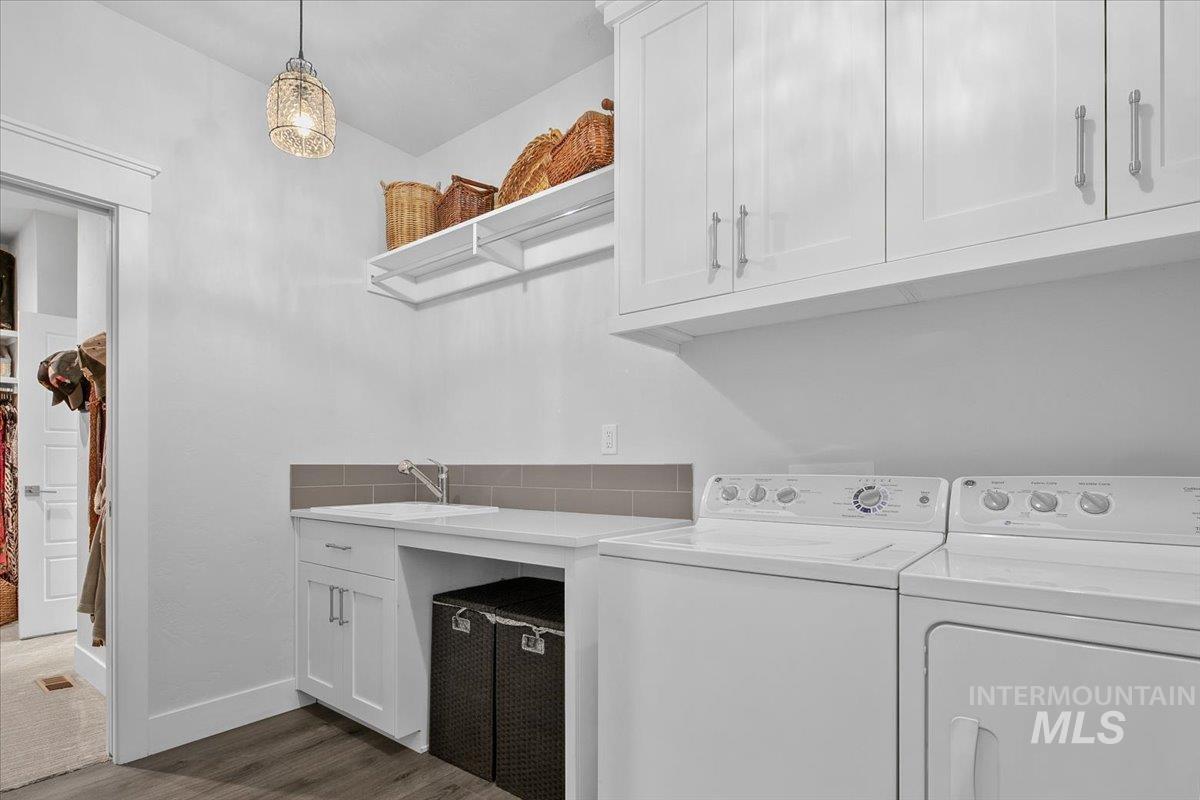 Washroom with washing machine and clothes dryer, dark wood-type flooring, and cabinet space
