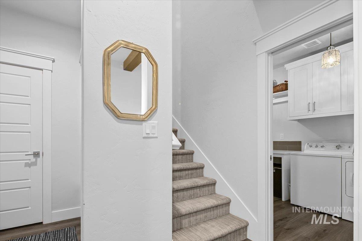 Stairs featuring wood finished floors and washing machine and clothes dryer