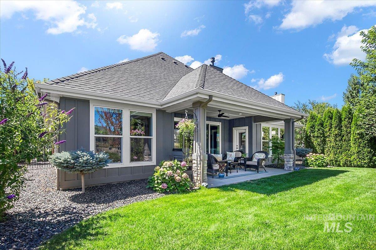 Rear view of house featuring a patio area, ceiling fan, a yard, and roof with shingles
