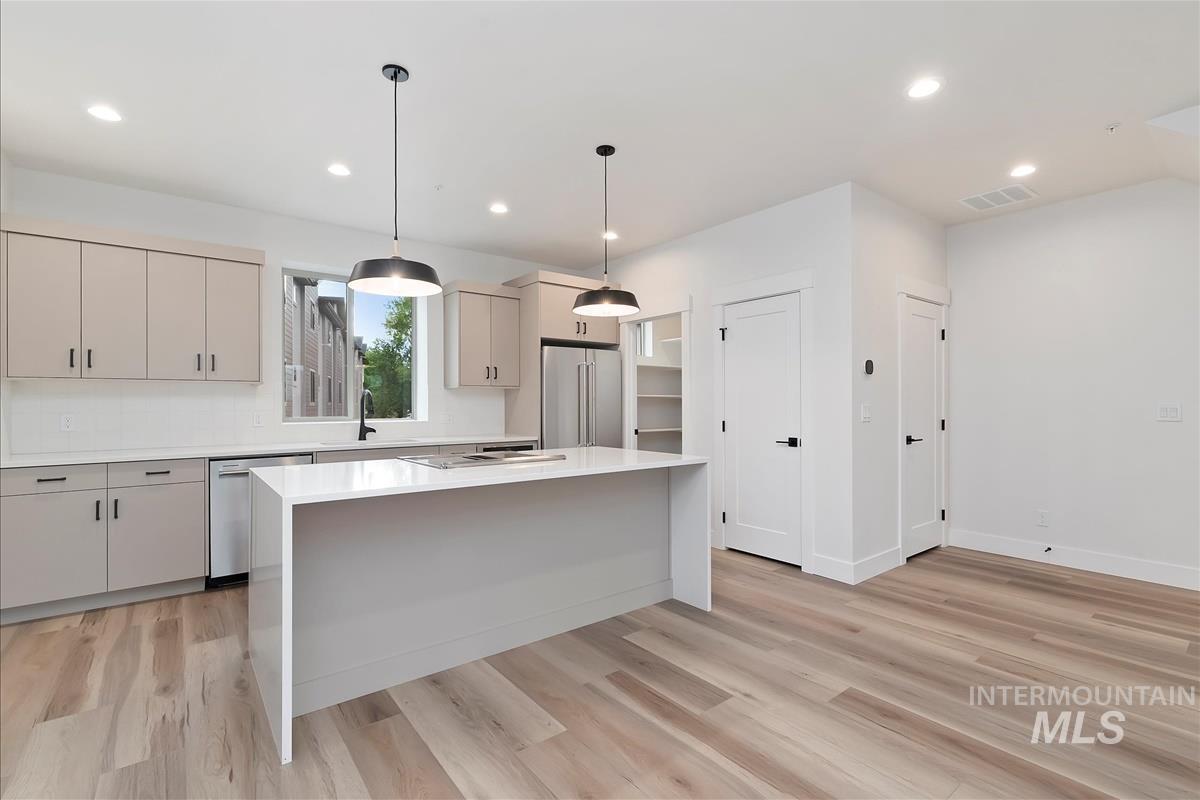 Kitchen with decorative light fixtures, a center island, recessed lighting, light wood-style flooring, and appliances with stainless steel finishes