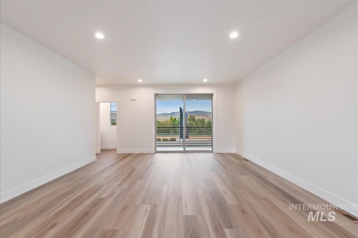 Empty room featuring recessed lighting, light wood-style floors, and a mountain view