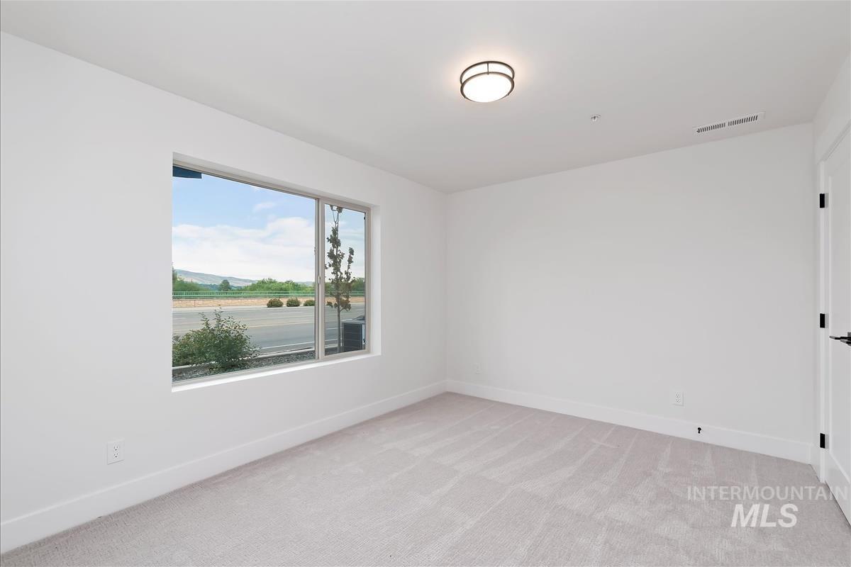 Spare room featuring light colored carpet and baseboards