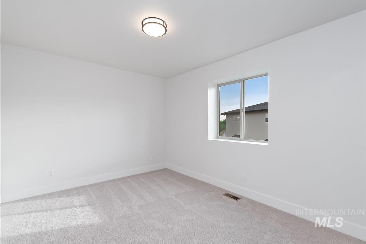 Spare room featuring light colored carpet and baseboards
