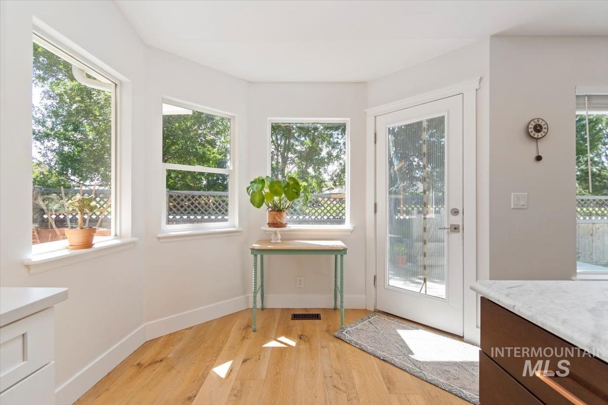 Doorway with light wood finished floors and baseboards