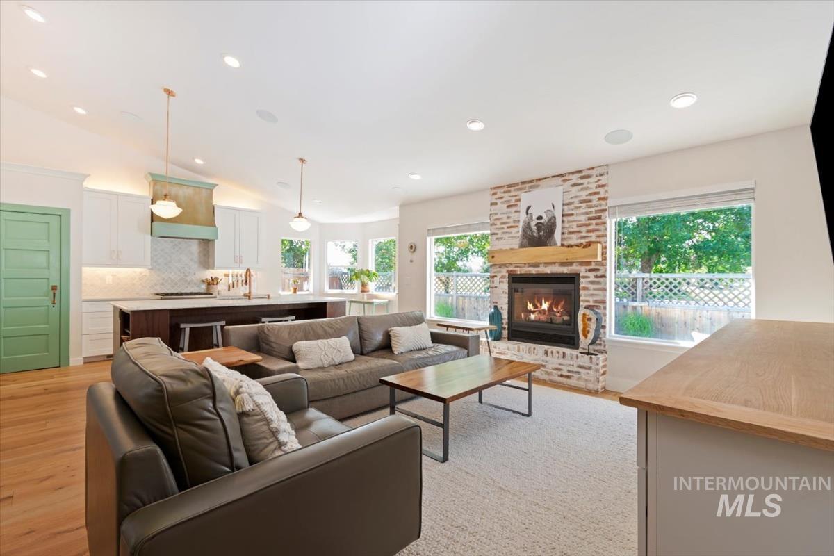 Living area with vaulted ceiling, a fireplace, light wood-style flooring, and recessed lighting
